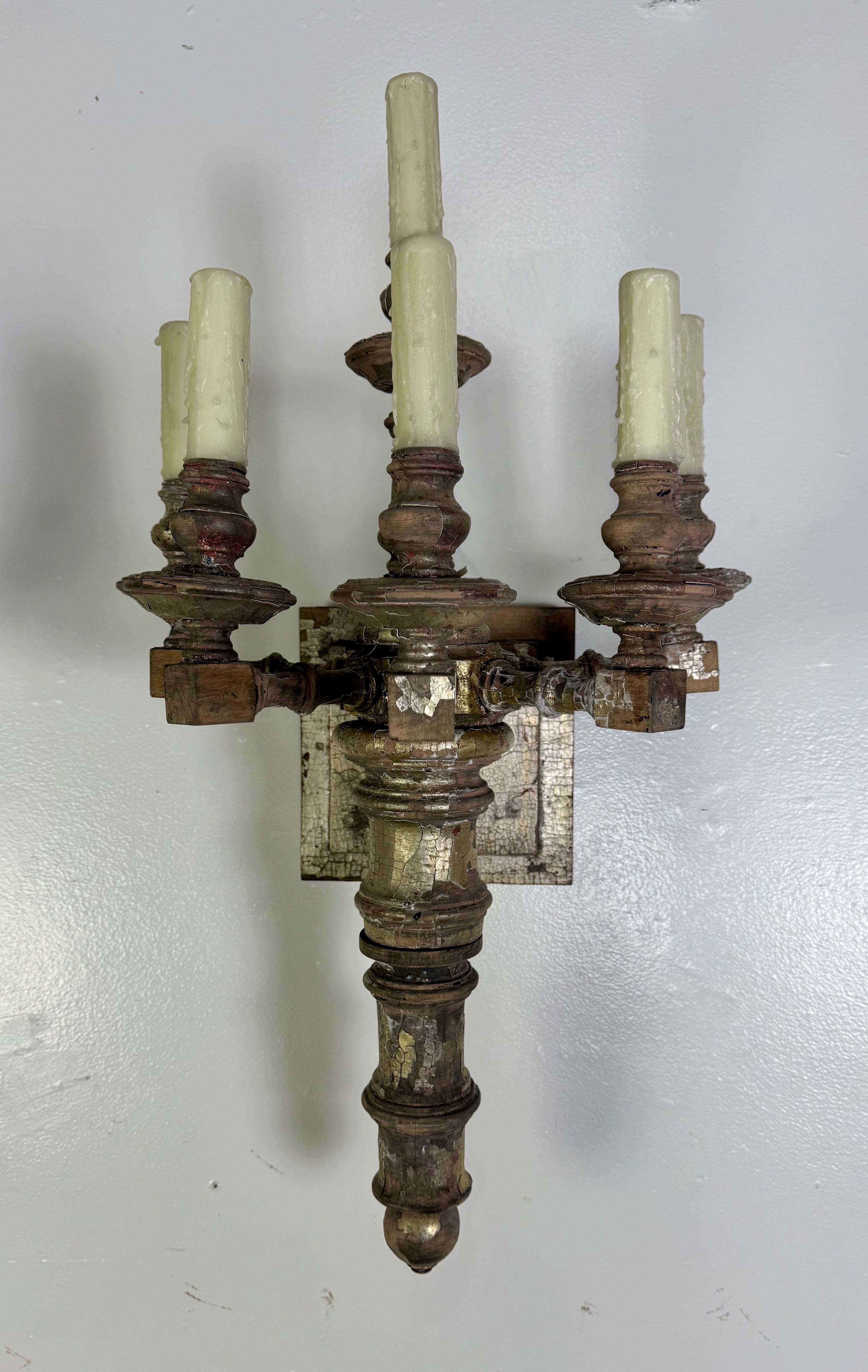 Pareja de apliques de cinco luces de madera dorada tallada a mano

Un dramático y escultural par de apliques de pared, cada uno elaborado a partir de fragmentos de madera ricamente patinados y tallados a mano con restos de plata vieja y dorado sobre