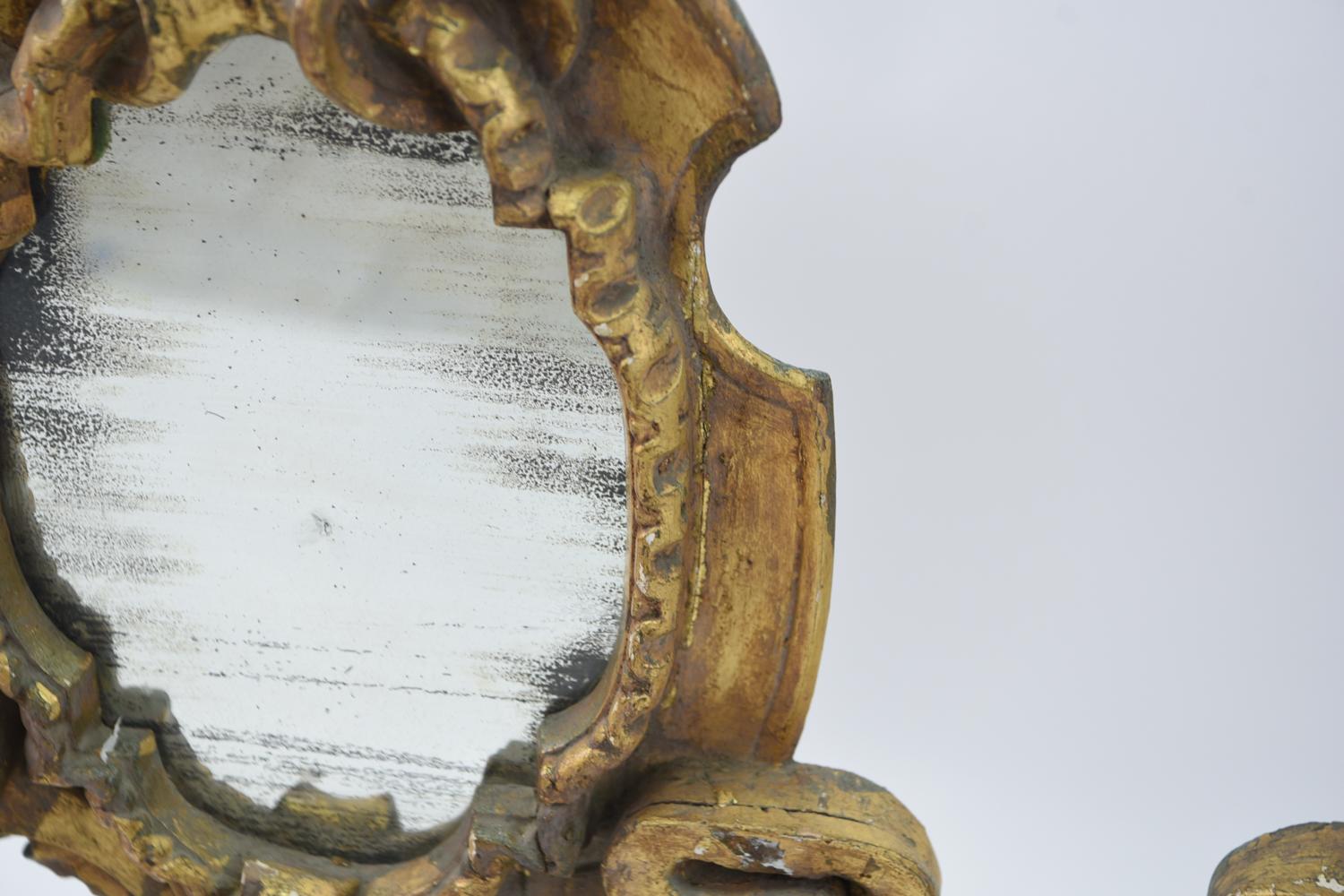 The substantiality and architectural look of this incredible pair of mirrors suggests that they may once have been part of a grand mantlepiece in a gentleman's home. With their warm gold gilding, interesting wooden applique, and neoclassical carved