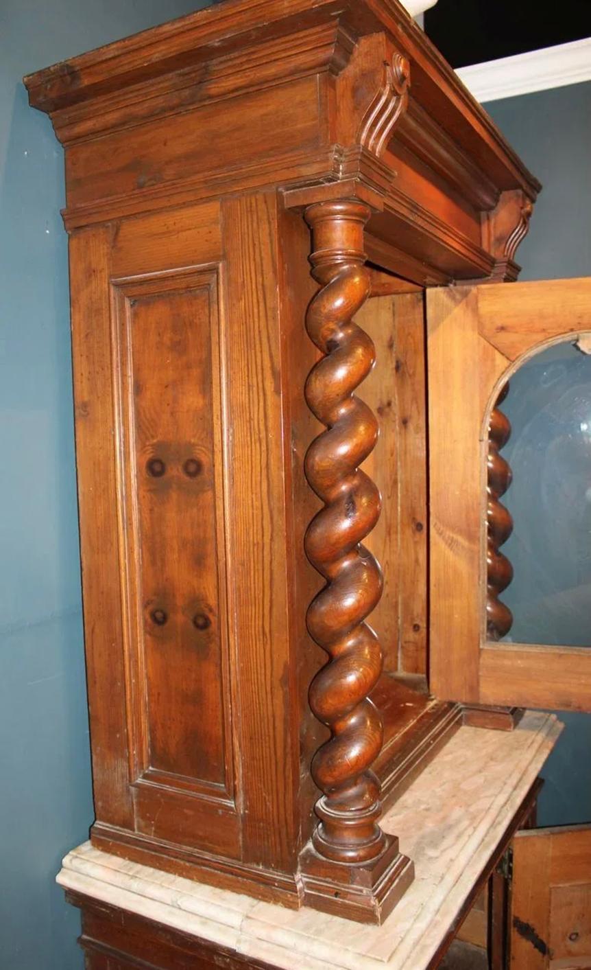 Pair of late 19th century Italian cabinets, probably walnut,  in two sections. The upper sections with arched glass doors flanked by Solomonic columns all resting on cupboard bases with nicely molded stone tops and paneled doors. Upper sections are