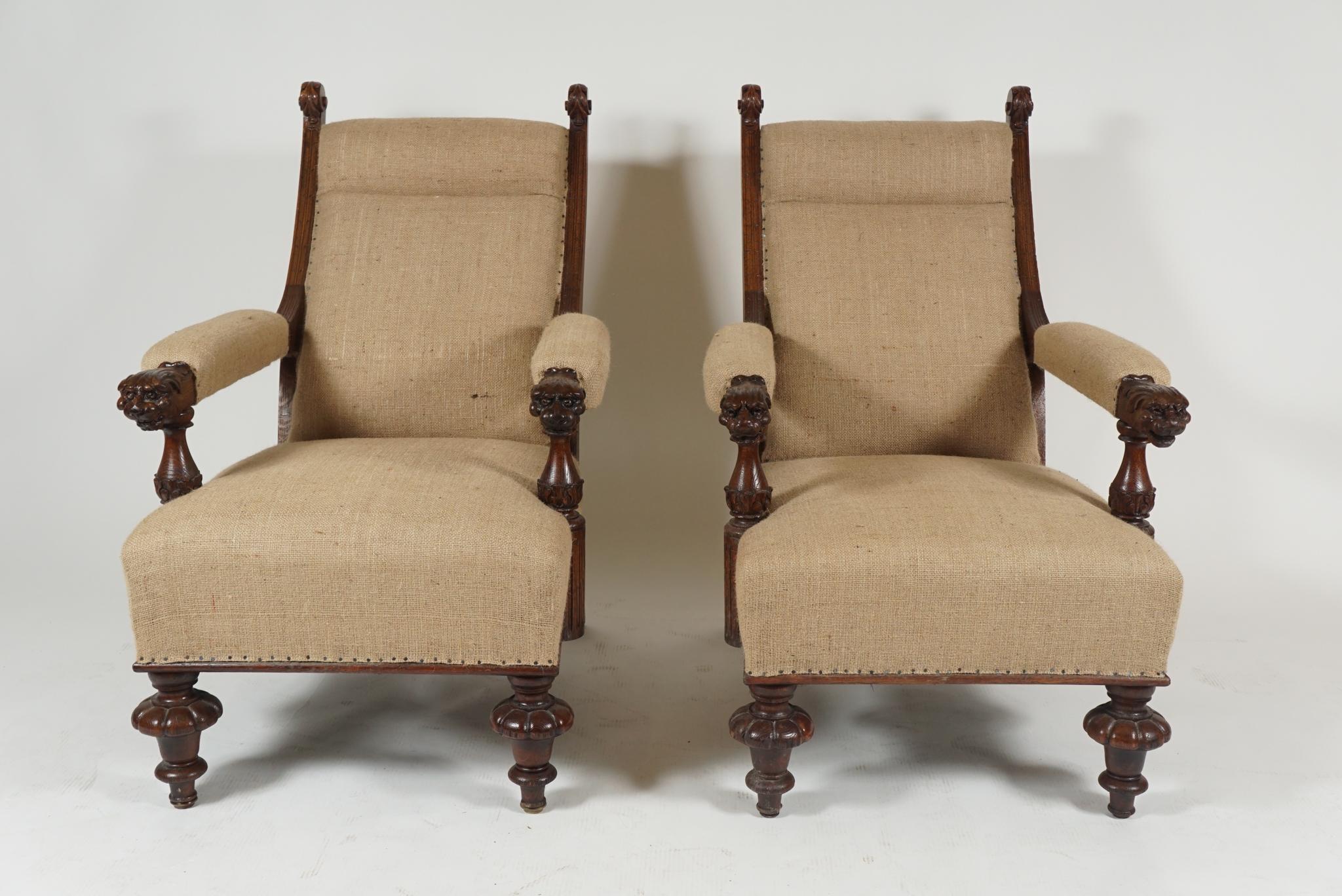 Pair of late 19th century oak library armchairs with arms terminating in lion head carvings and turned legs in walnut. 
The chairs newly upholstered in a textured burlap fabric.
 