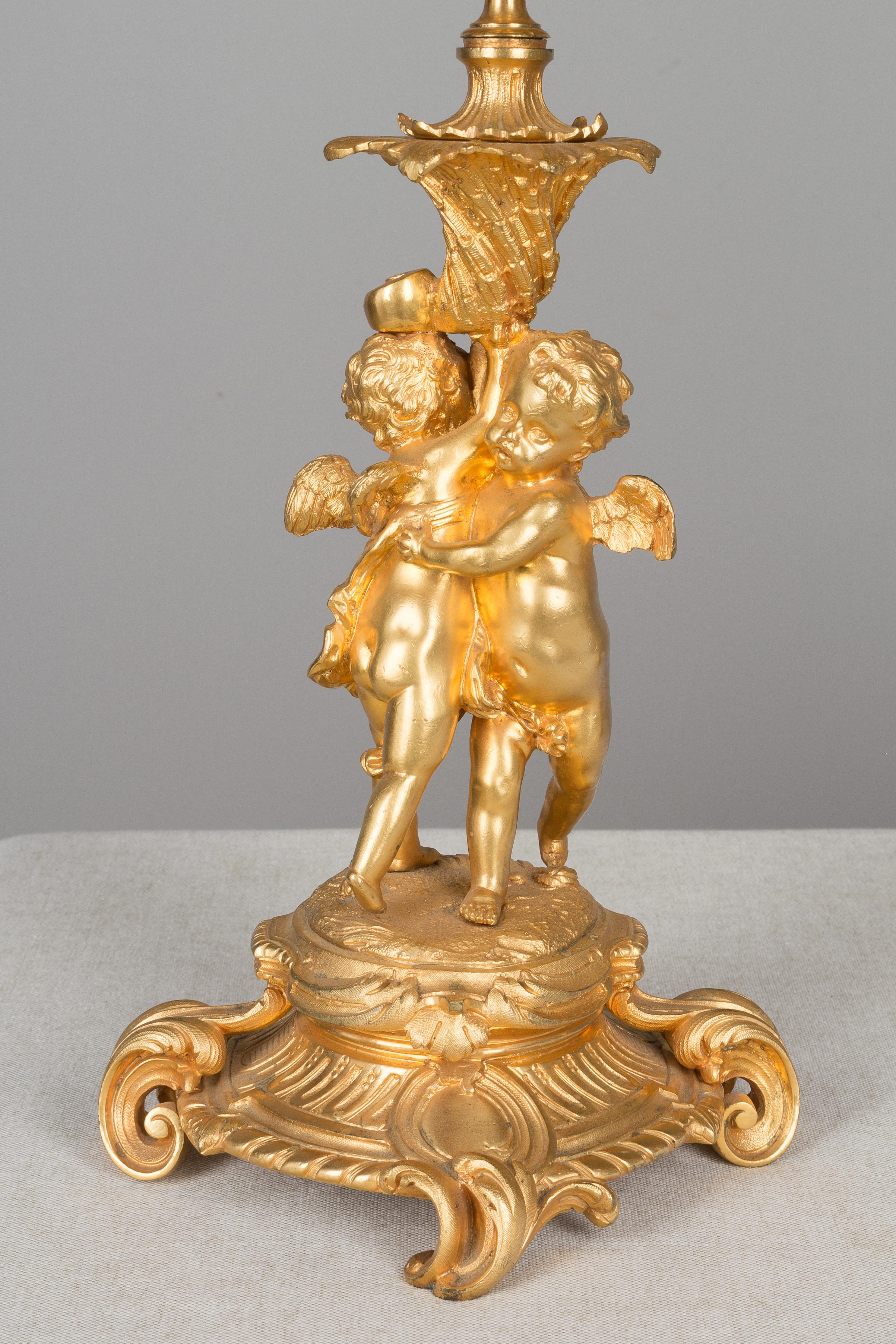 A pair of grand 19th century Louis XV style ormolu candelabra, each constructed in gilt bronze and depicting a pair of putti embracing on a shaped footed base and holding aloft a seven-light candelabra with leaf adorned branches. Finely cast in two