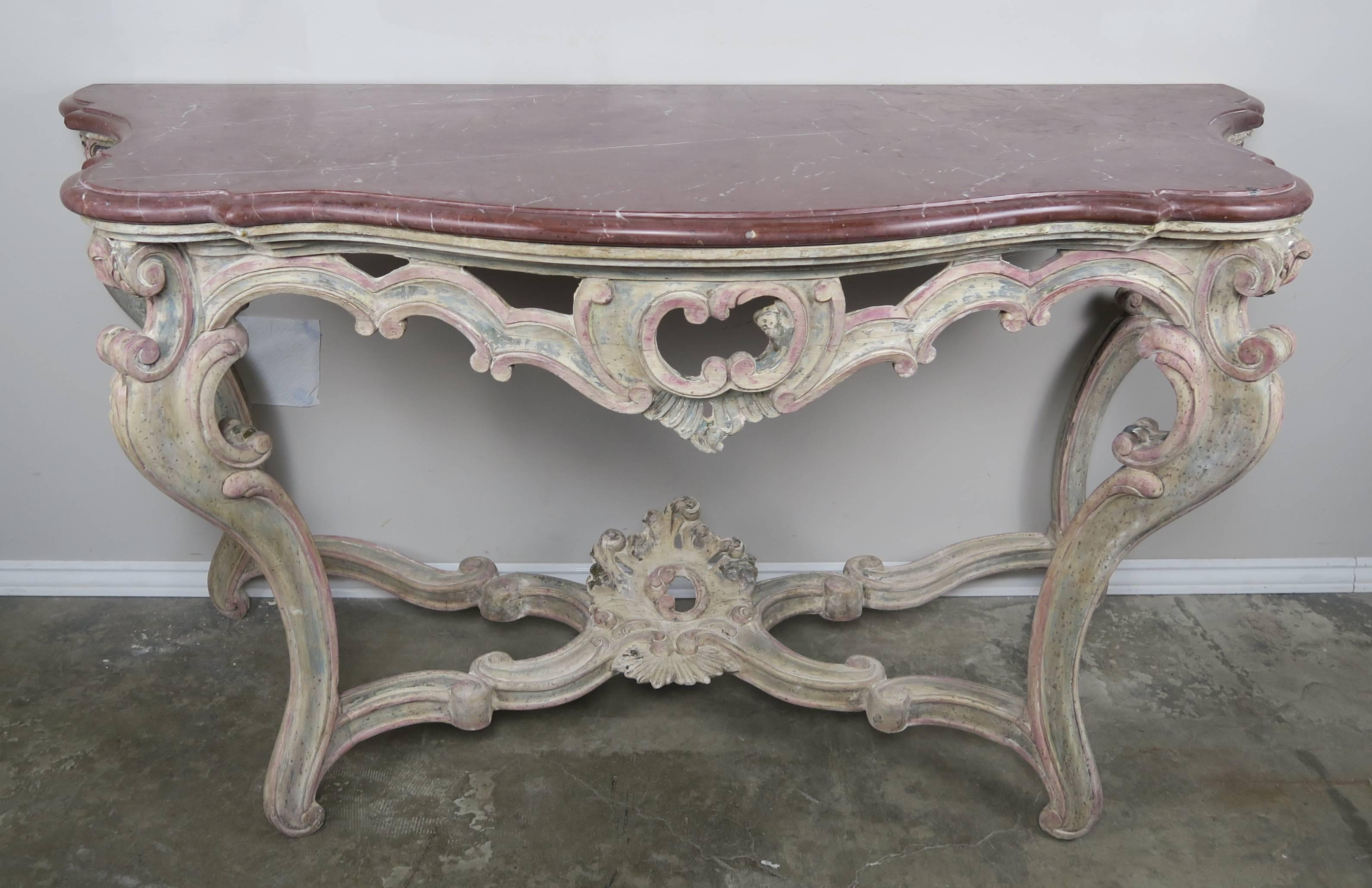 Pair of French 19th century Louis XV style carved walnut consoles with serpentine shaped honed terra cotta colored marble tops. The marble tops are finished with a single ogee, bullnose edge detail.