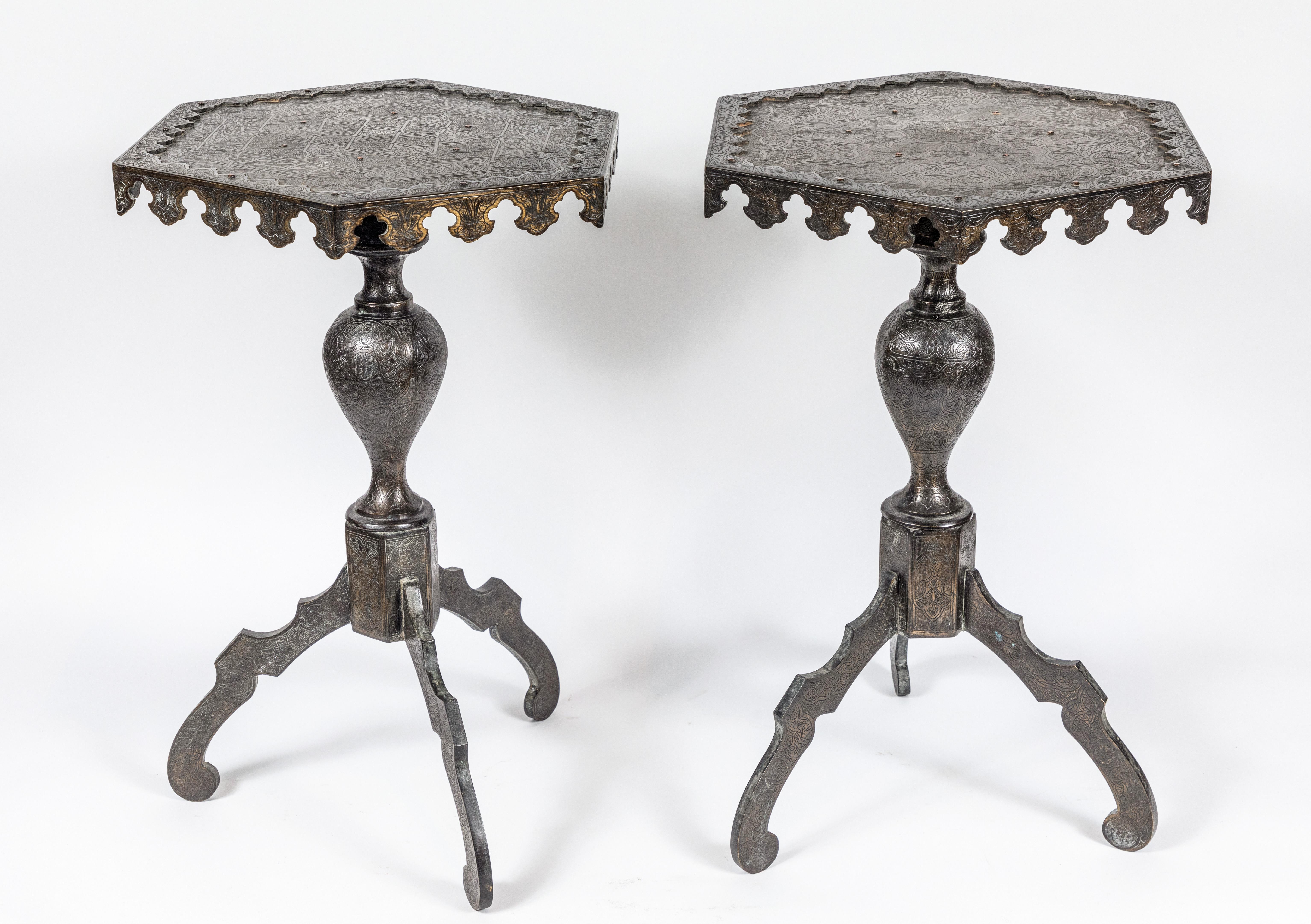 Unusual pair of cast bronze, tripod-based, pedestal tables, elaborately incised throughout with foliate details and Arabic writing. The top surrounded by raised edges terminating in a modified, scalloped border.