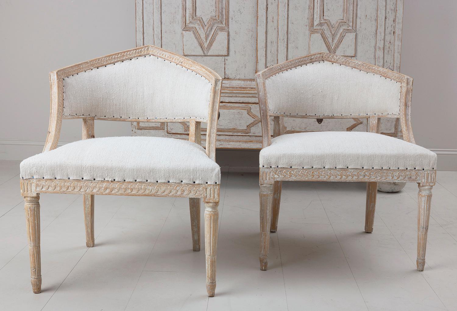 A pair of Swedish chairs with unique sulla barrel backs. Stunning chairs from the Gustavian period wearing original paint and newly upholstered in antique linen with nail head trim. Beautifully carved guilloche pattern around the backs of the chairs
