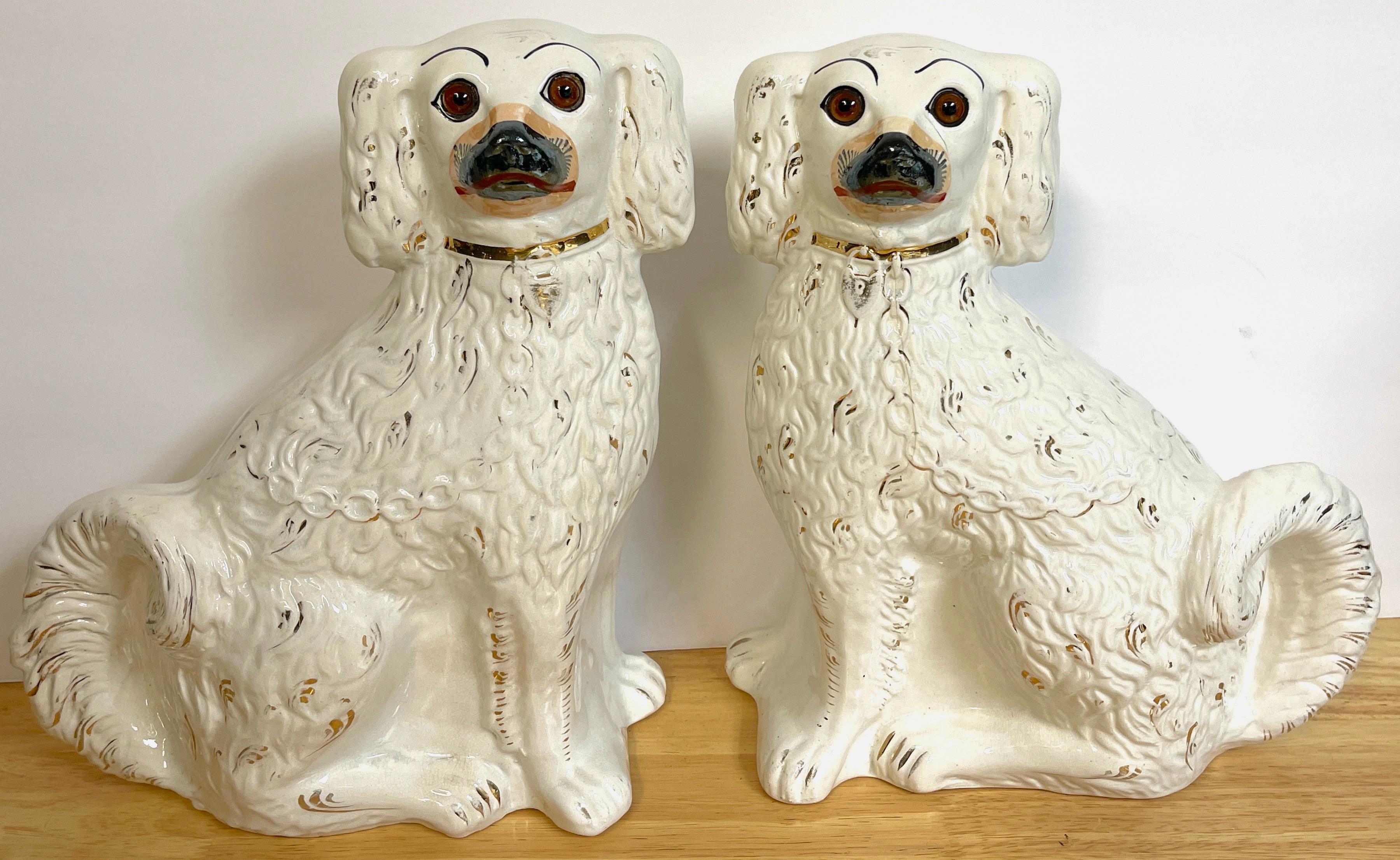 Pair of 19th century white & gilt decorated Staffordshire dogs, an unusual pair, well painted and modeled. Each one a standing spaniel with inset glass eyes and an extended back leg, nice patina.
