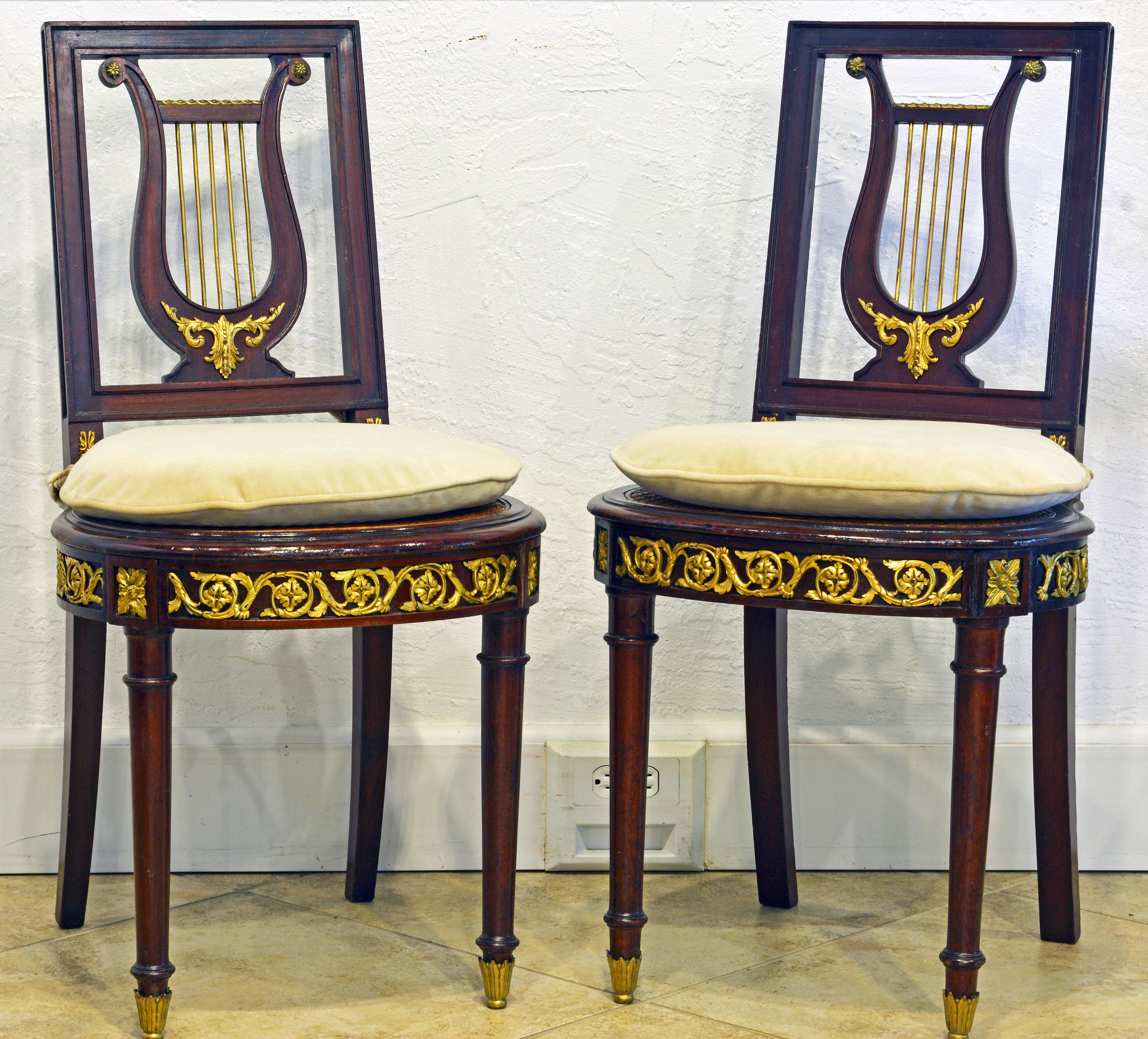 Dating to the late 19th century these elegant richly ormolu mounted French side chairs have caned seats in good condition, but tasteful cushions have been made for increased comfort. These are beautiful accent chairs eventually for a music room.