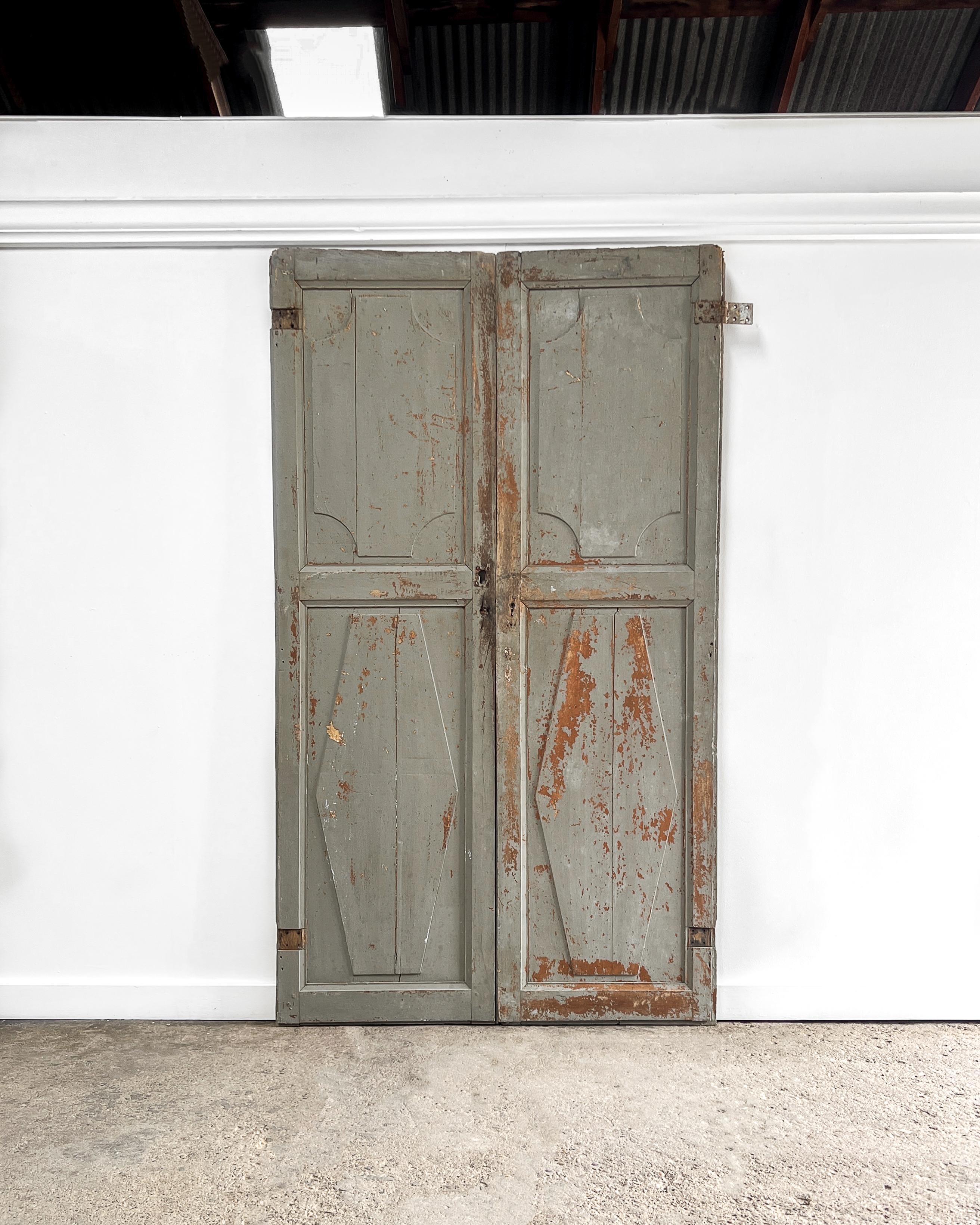 A pair of 19th-century antique French wardrobe doors. Handcrafted from solid wood, the front side of the doors feature two panels with decorative scalloped corner details, while the interior of the doors is a straightforward 3-panel