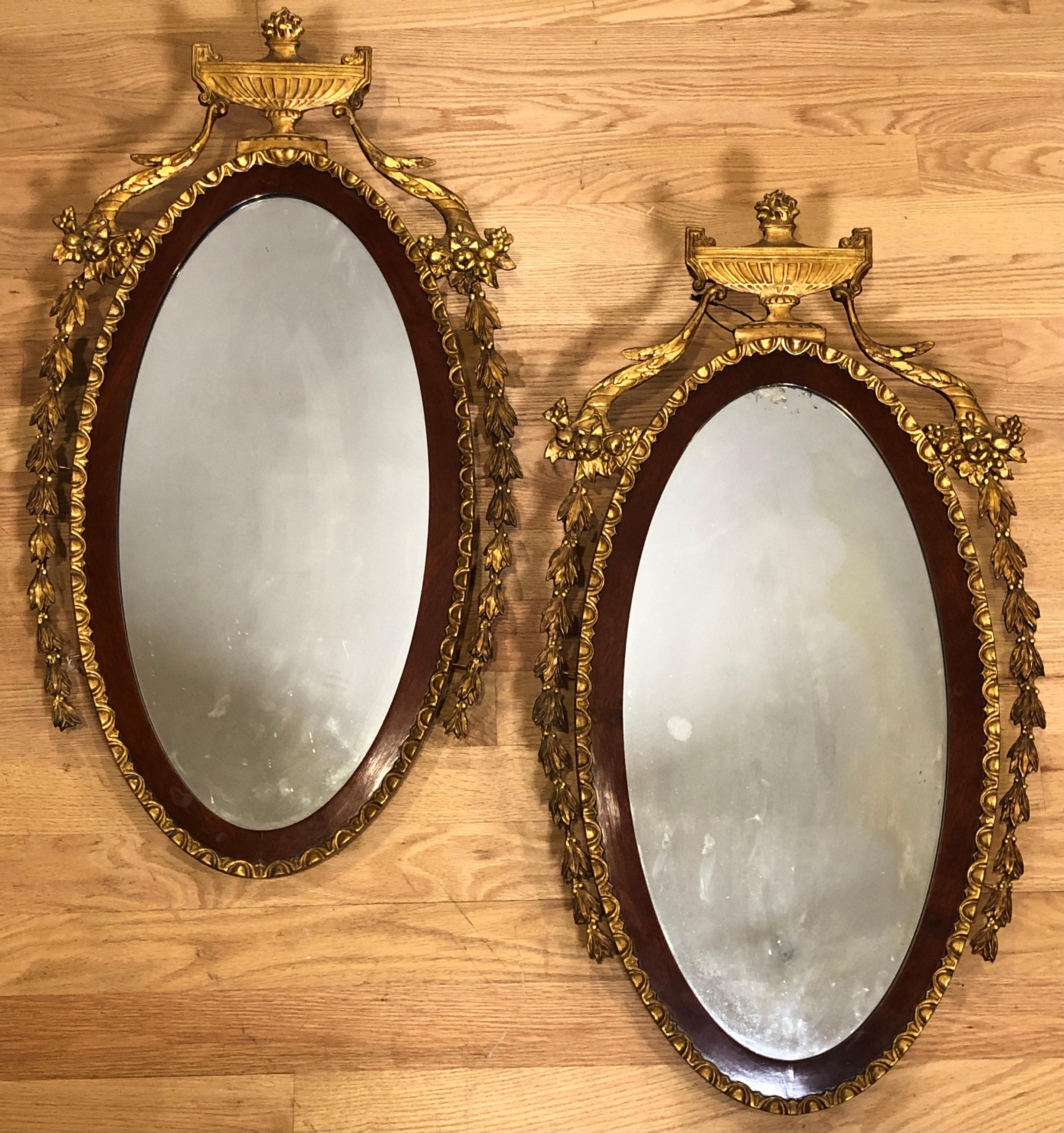 Matched pair of 19th century Adam style giltwood and mahogany mirrors. Centered urns, laurel leaves and cornucopia elements.