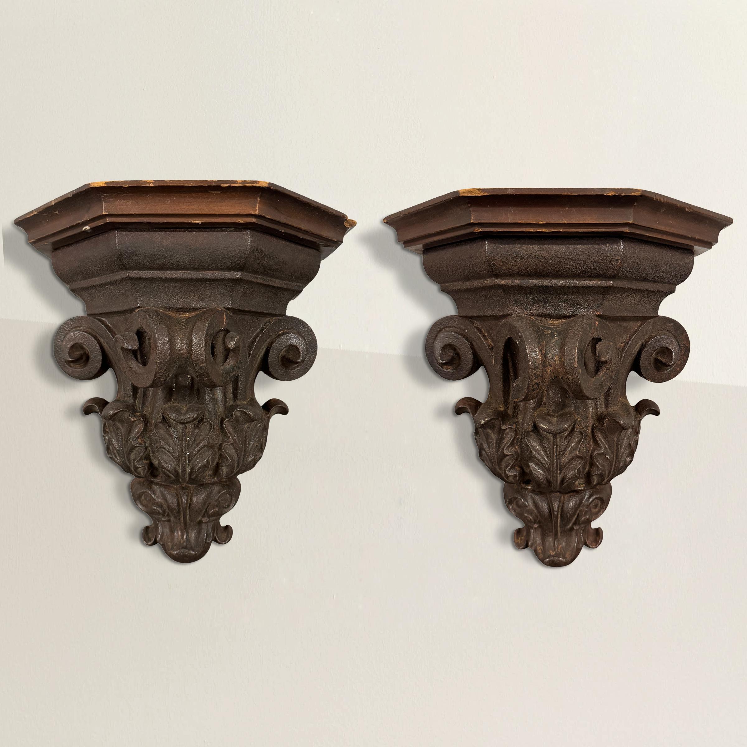 This pair of 18th-century American cast iron wall brackets brings sculptural weight and classical elegance to any room. Each bracket is cast with refined architectural detail—Doric-inspired volutes curl gracefully at the top, while acanthus leaves