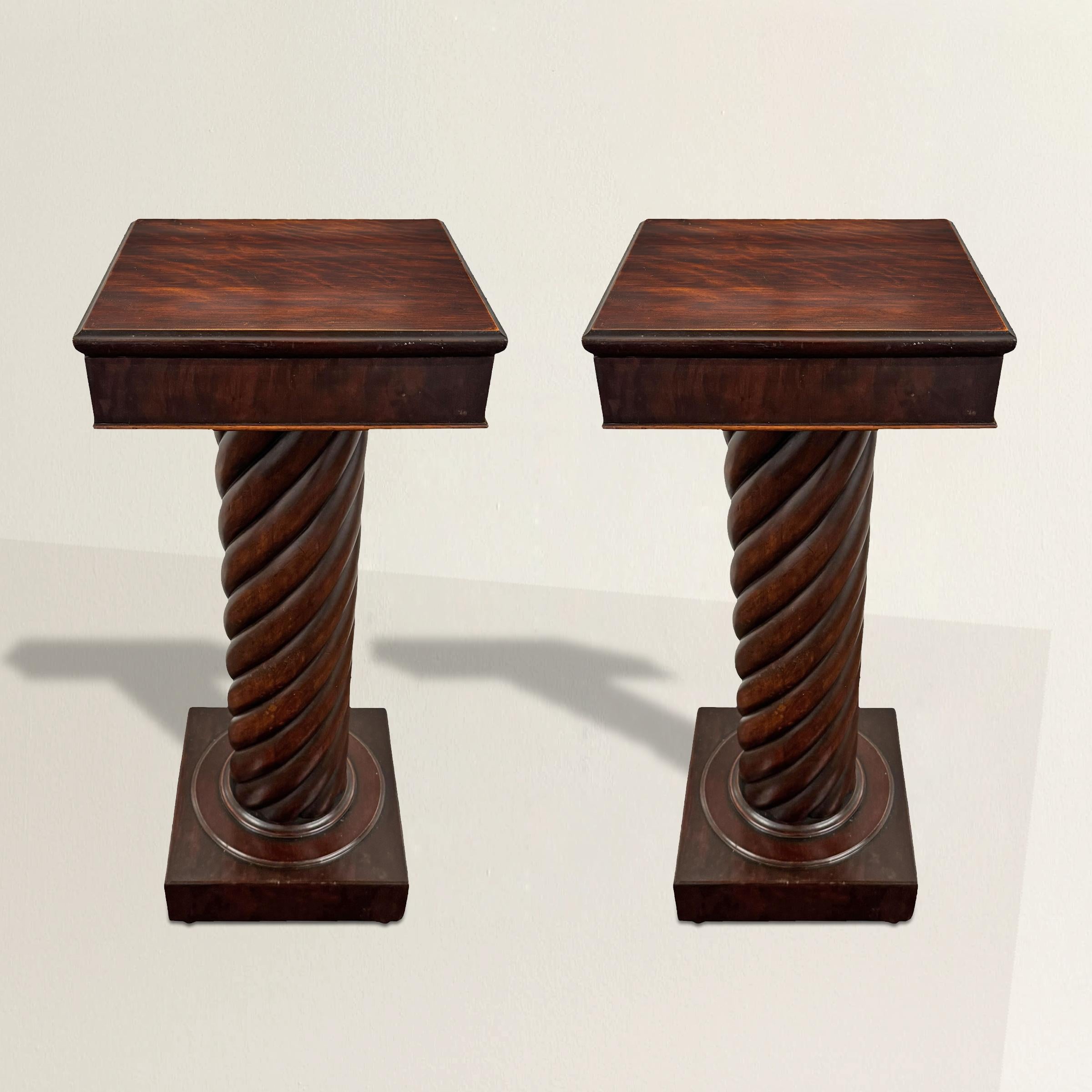 Un majestuoso par de pedestales Imperio Americano del siglo XIX, fabricados en caoba ricamente labrada con un acabado profundo y luminoso. Cada soporte presenta una columna de torsión de cebada de escala audaz, expertamente tallada para mostrar