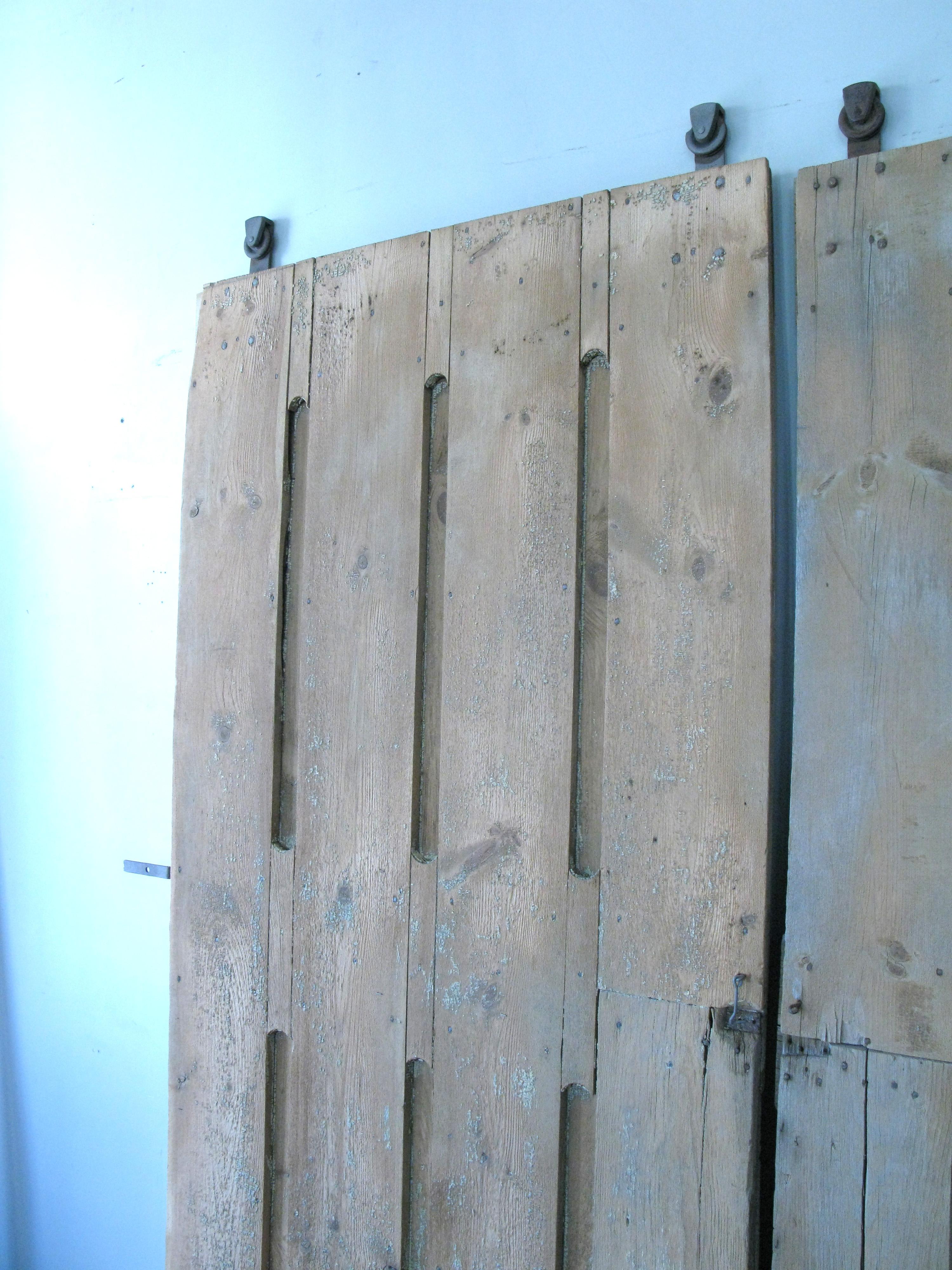 A pair of late 19th century american Gothic barn doors, with their original rolling hanging wheels. really great design and heavy and well made. these have been stripped of their old paint.