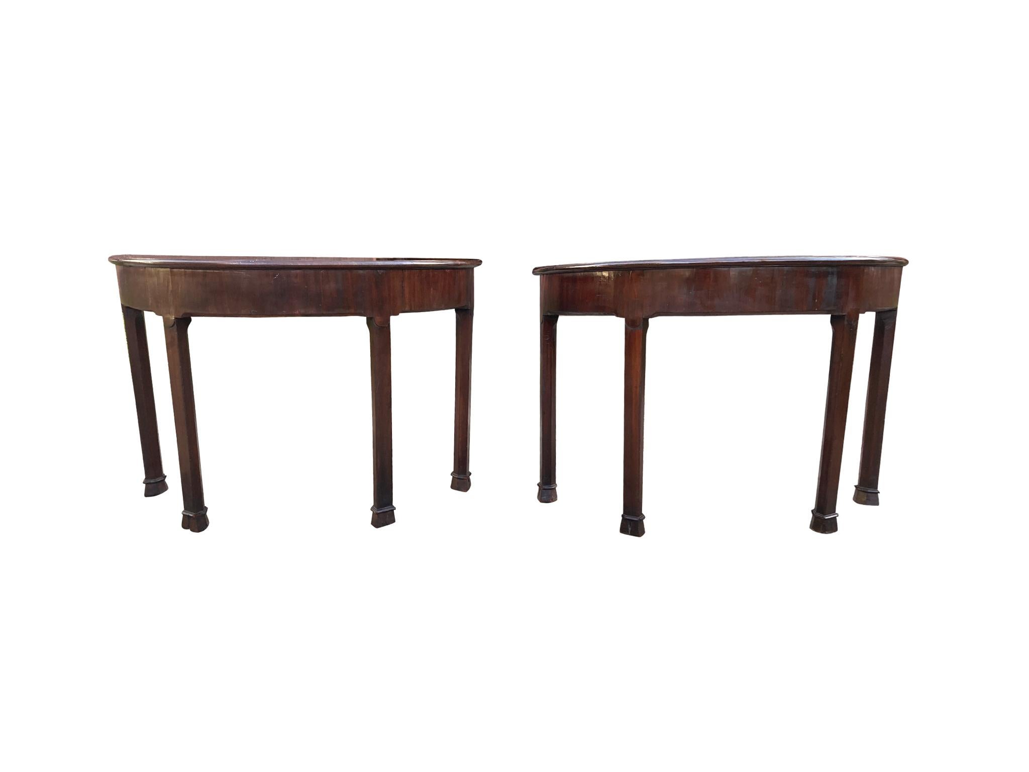A lovely pair of American demilune tables, crafted in the 19th century. They are comprised of mahogany with mahogany veneer. The design is classical in its simplicity and symmetry. We love the table's subtle decorative qualities: the beveled edge,