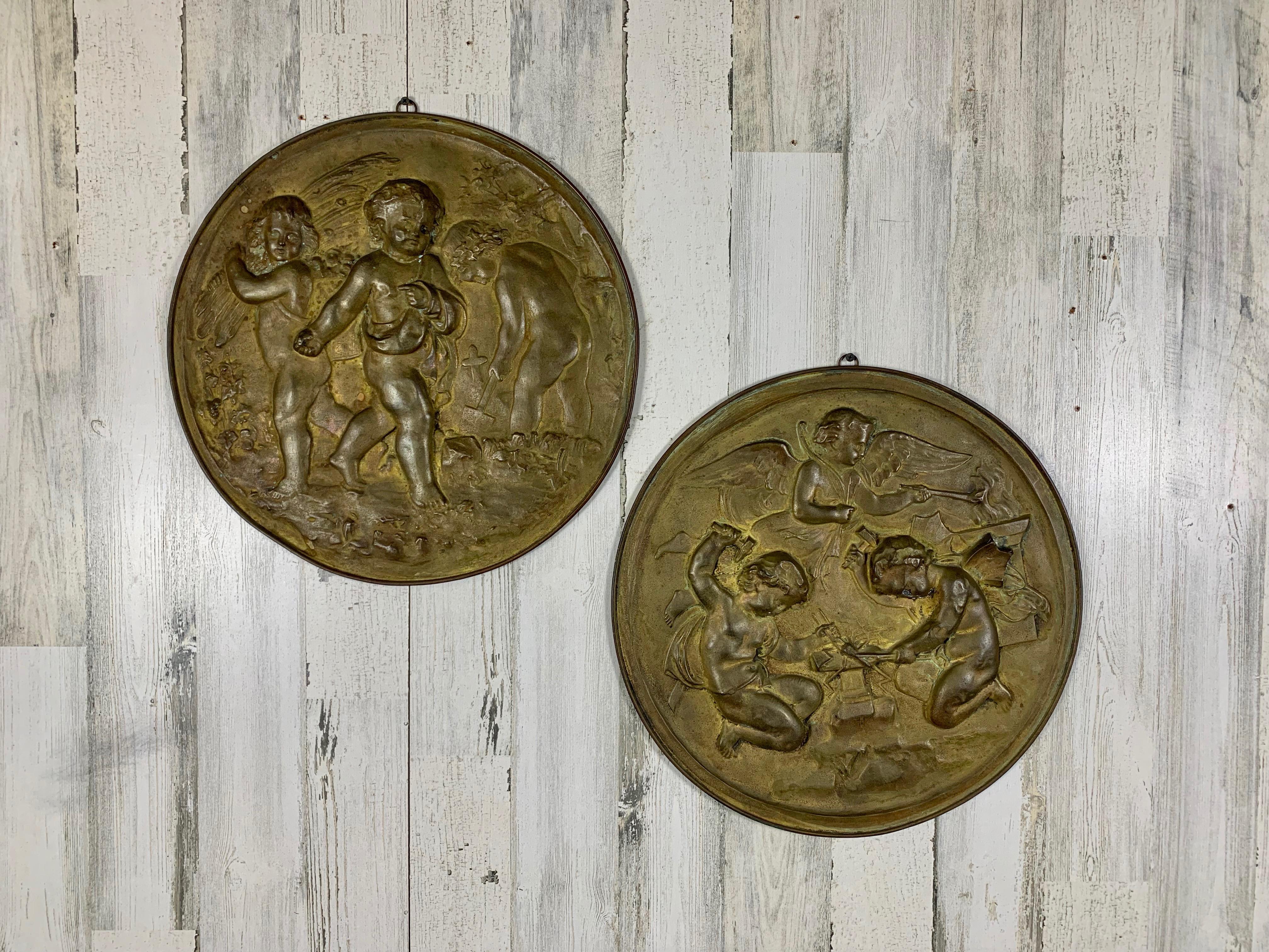 Pair of Antique 19th century angels at work brass repousse decorative rounds 
One depicting harvesting the fields and the other refining by fire to forge a new creation.