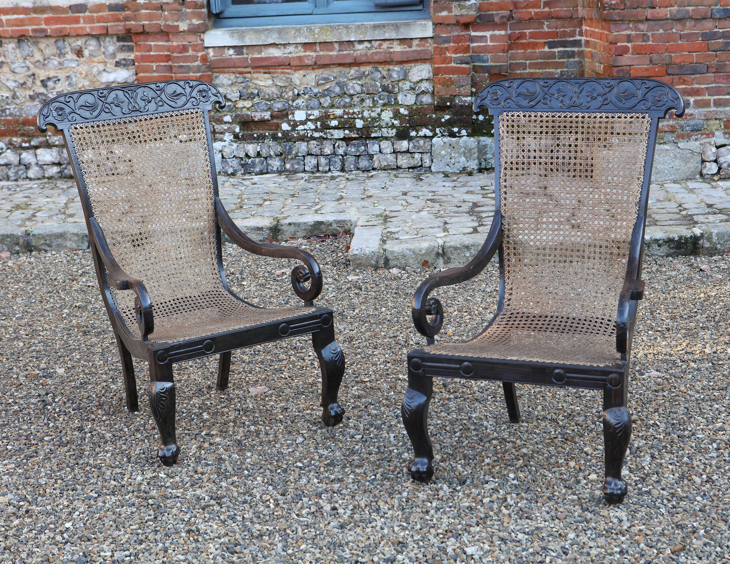 Pair of Anglo-Indian solid ebony caned armchairs, the ebony frames carved with delicate trailing vines across the top rails, the sweeping frames with scroll arms and raised on cabriole legs with claw feet.
India, circa 1850

Measures: Height