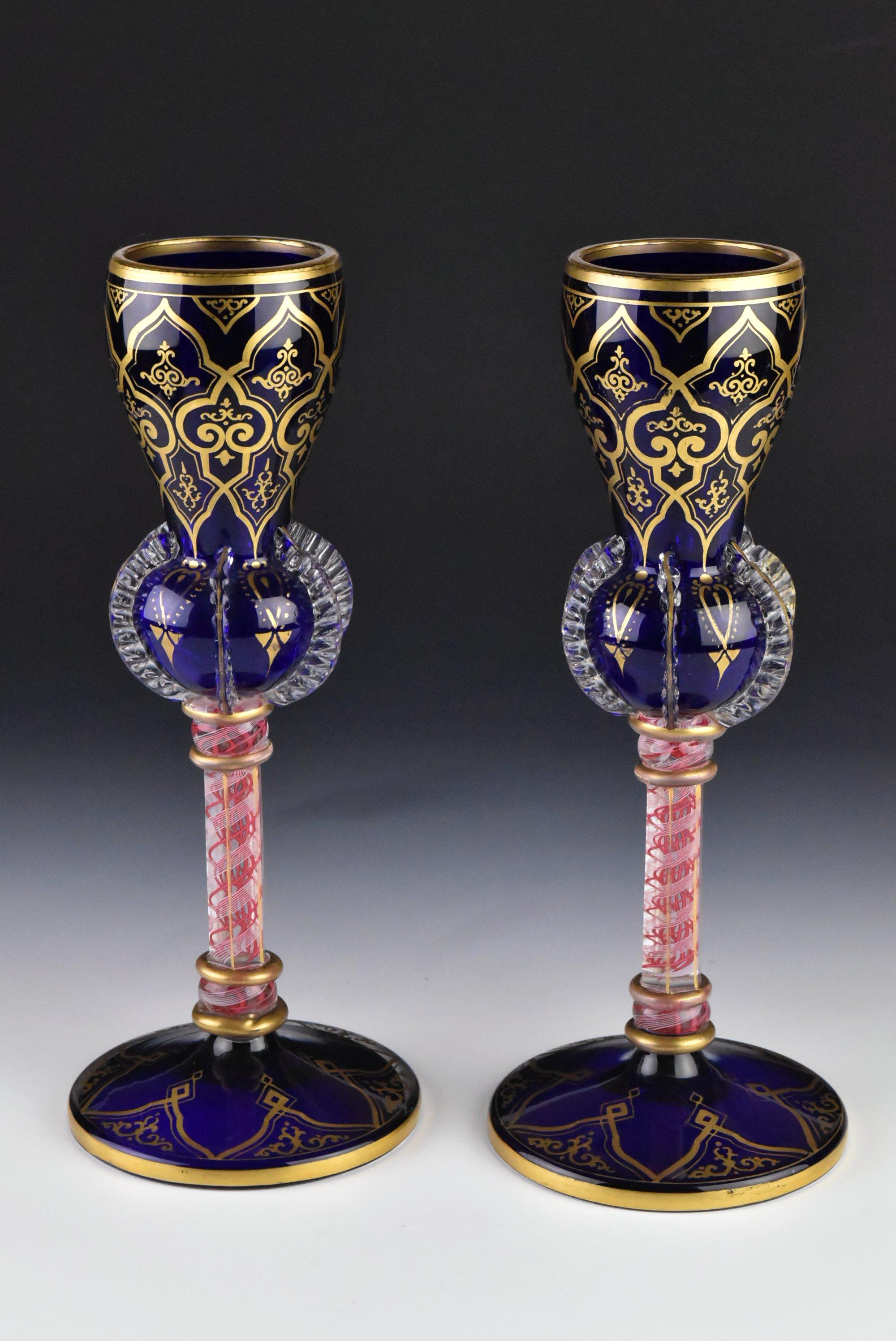 Description: Pair antique blown stem goblets with cobalt blue tops and clear over blue bases. They have applied riggory with facet cut clear glass stems decorated with pink ribbon threading twisting inside white swirl. They are highlighted with gold