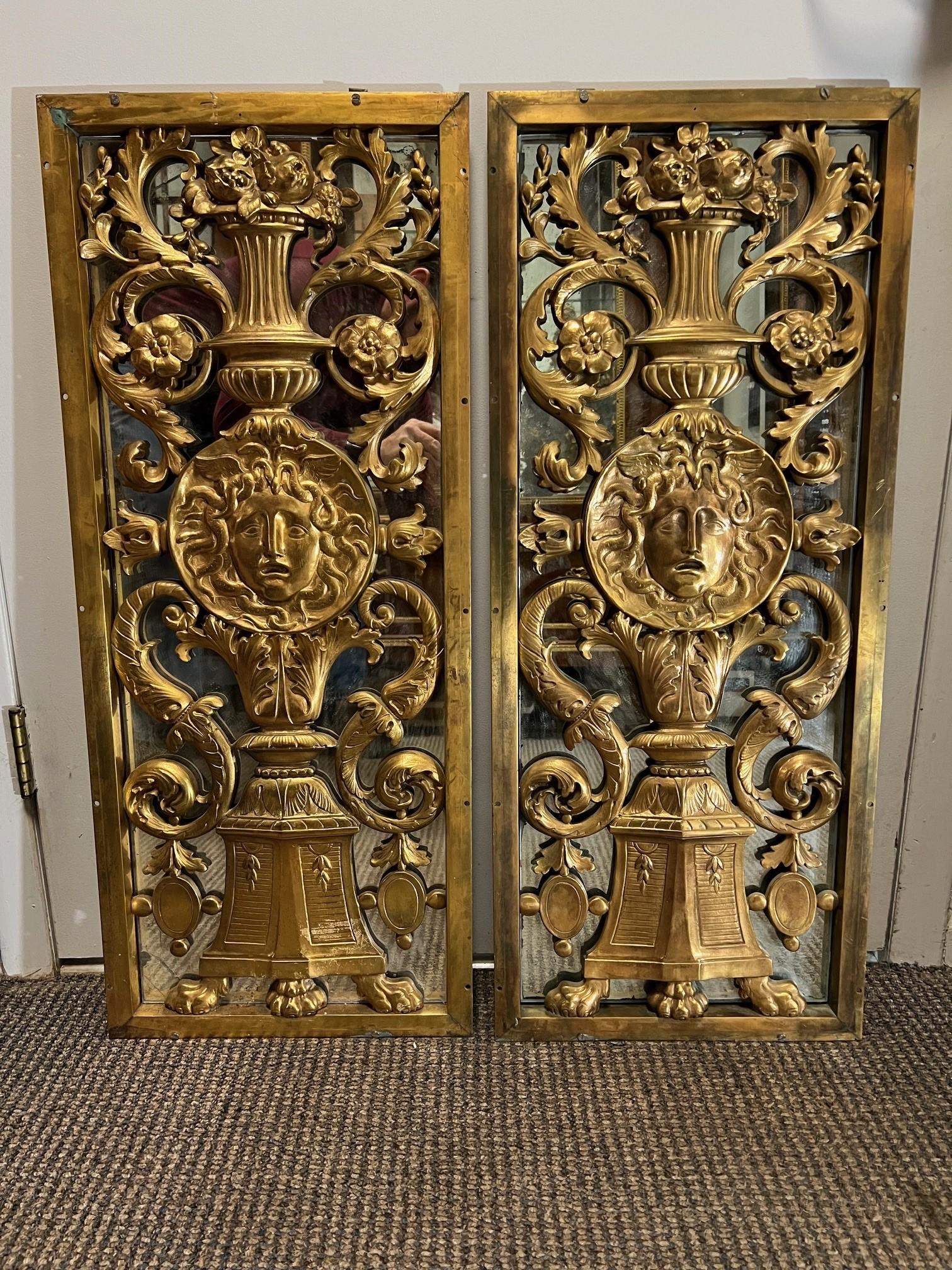 Very ornate pair of 19th century antique cast bronze panels with the face of Medusa in the center. In the panel the bottom has a footed pedestal with a urn above and beautiful flowers and scroll work. Medusa in Greek mythology also called Gorgo, was