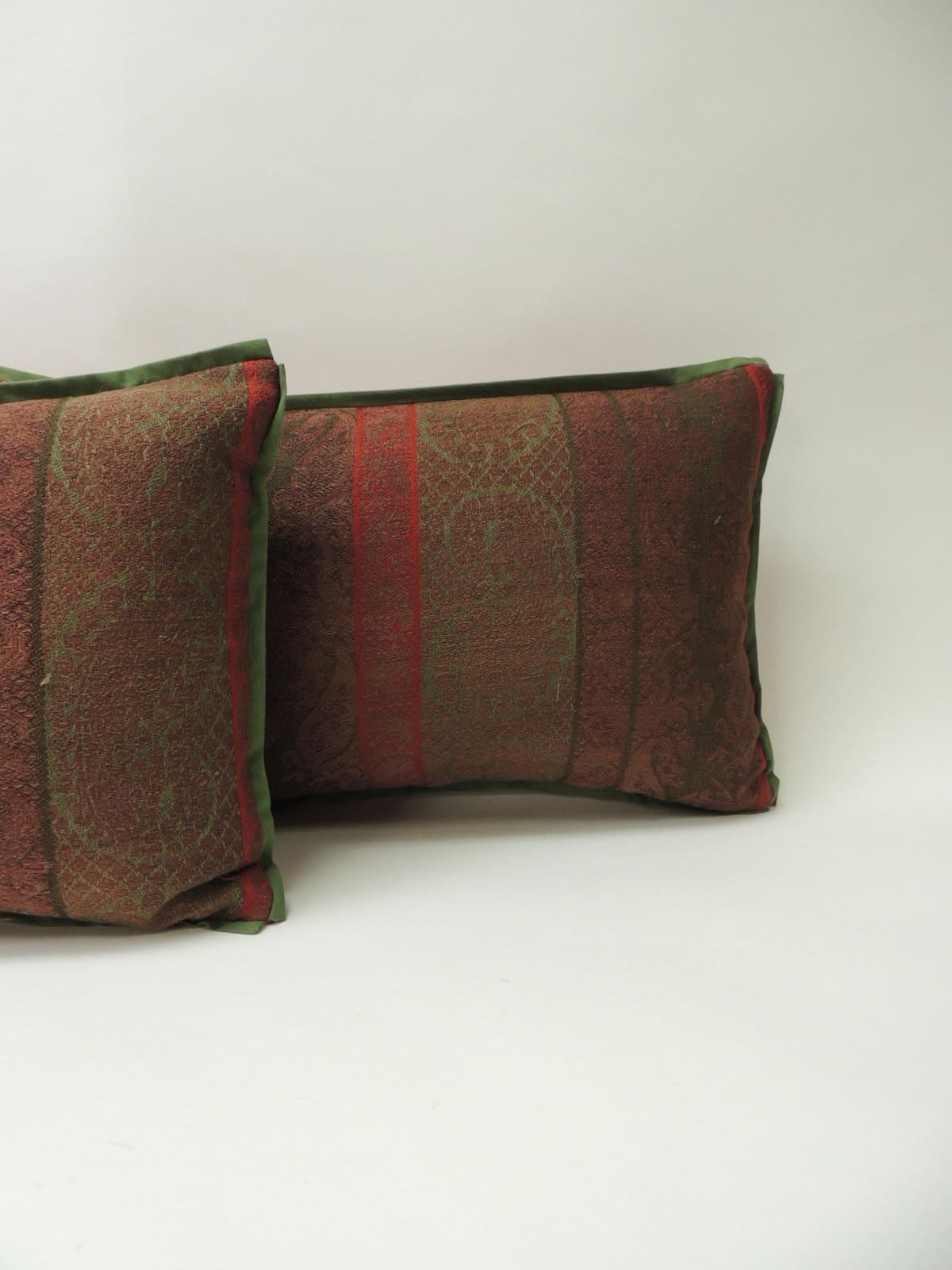Pair of 19th century antique woven Kashmir decorative pillows with green flat cotton trim and red carriage cloth fabric backing.
In shades of brown, green, red and soft green. Handcrafted decorative pillow made with an antique textile fragment from