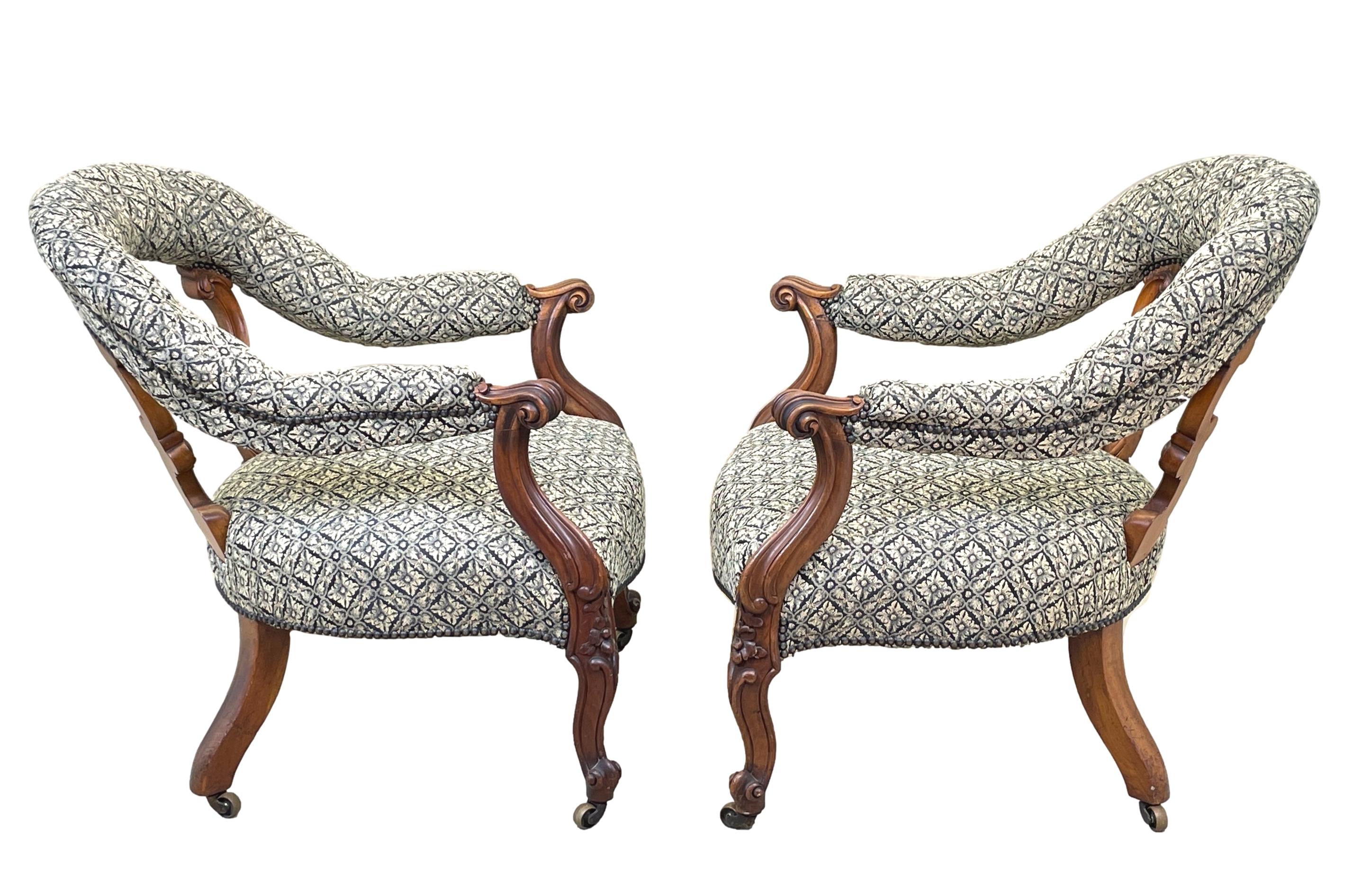 A very good quality pair of mid 19th century Victorian walnut tub library armchairs having unusual hoop type open backs with carved c scroll type upright supports over seat with scrolling arms raised on elegant carved cabriole legs and