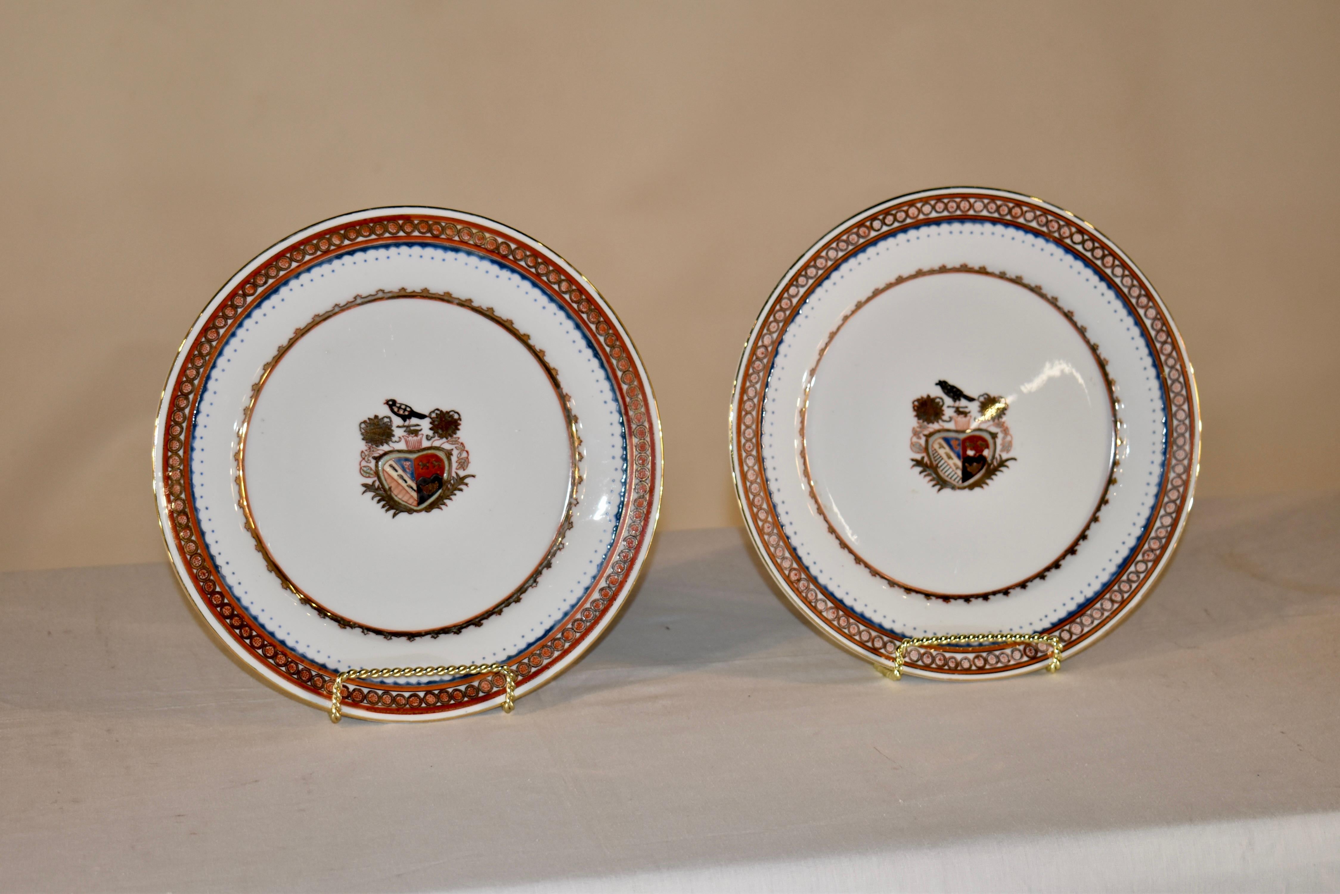 Pareja de preciosas placas armoriales de finales del siglo XIX procedentes de Inglaterra.  Los bordes están decorados en rojo ladrillo, dorado y azul marino.  La cenefa rodea el medallón central, que tiene un escudo pintado a mano con pájaros y