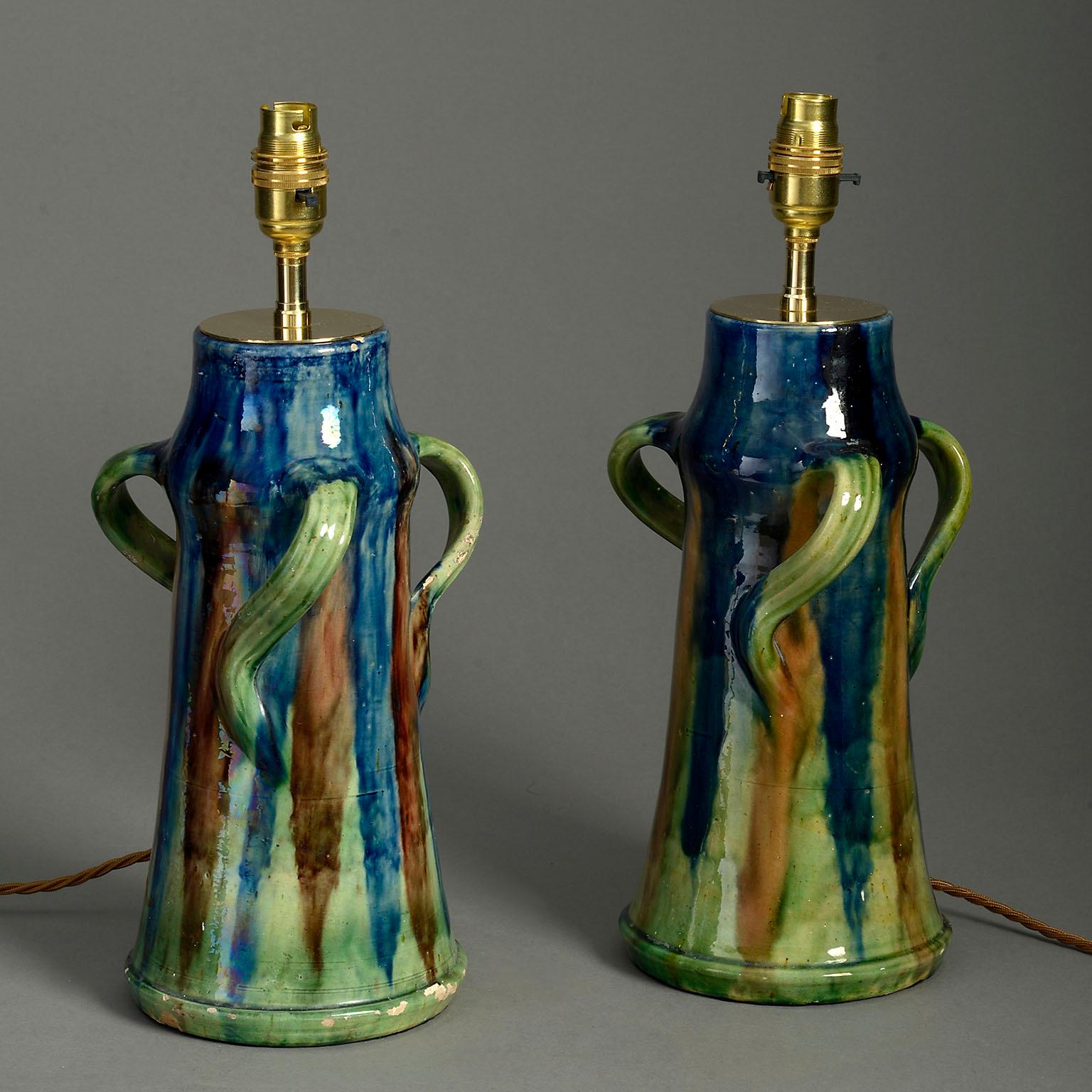 A pair of late nineteenth century iridescent polychrome glazed vases, each with three shapely handles and tapering conical bodies. Now mounted as table lamps.

Wired to UK standards but can be rewired for any international specification.