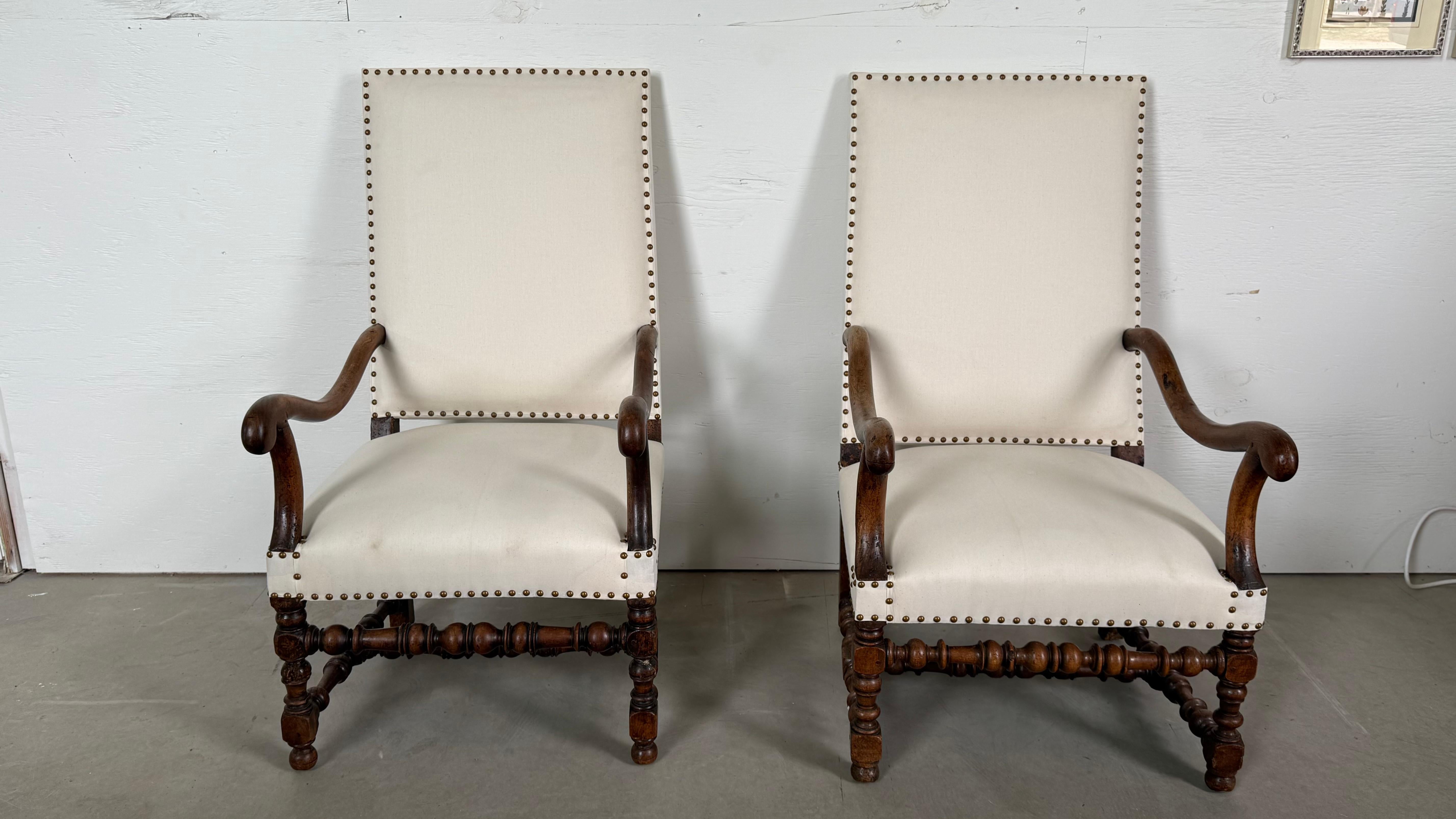 Audacieuse, sculpturale et empreinte de grandeur, cette paire de fauteuils de style Louis XIII capture l'essence du design baroque français du XVIIe siècle. Avec leur silhouette majestueuse, leurs pieds en chêne tournés et leurs accoudoirs à volutes