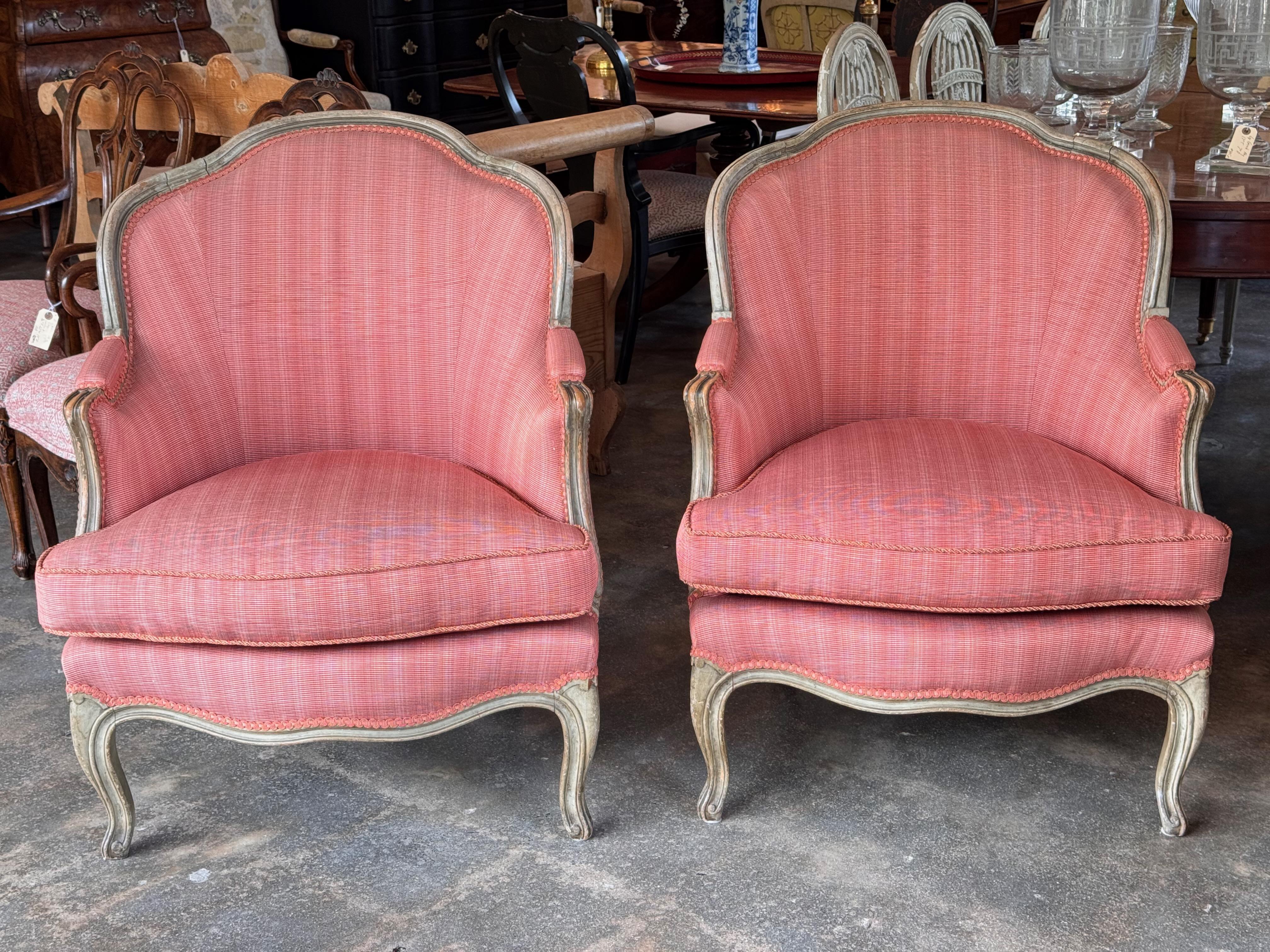 Coppia di bergeres francesi del XIX secolo con telaio in faggio dipinto, schienale sagomato e gambe a cabriola. I bordi intagliati conservano tracce di vernice originale, ora delicatamente consumata. Rivestite in un tessuto rosa testurizzato con