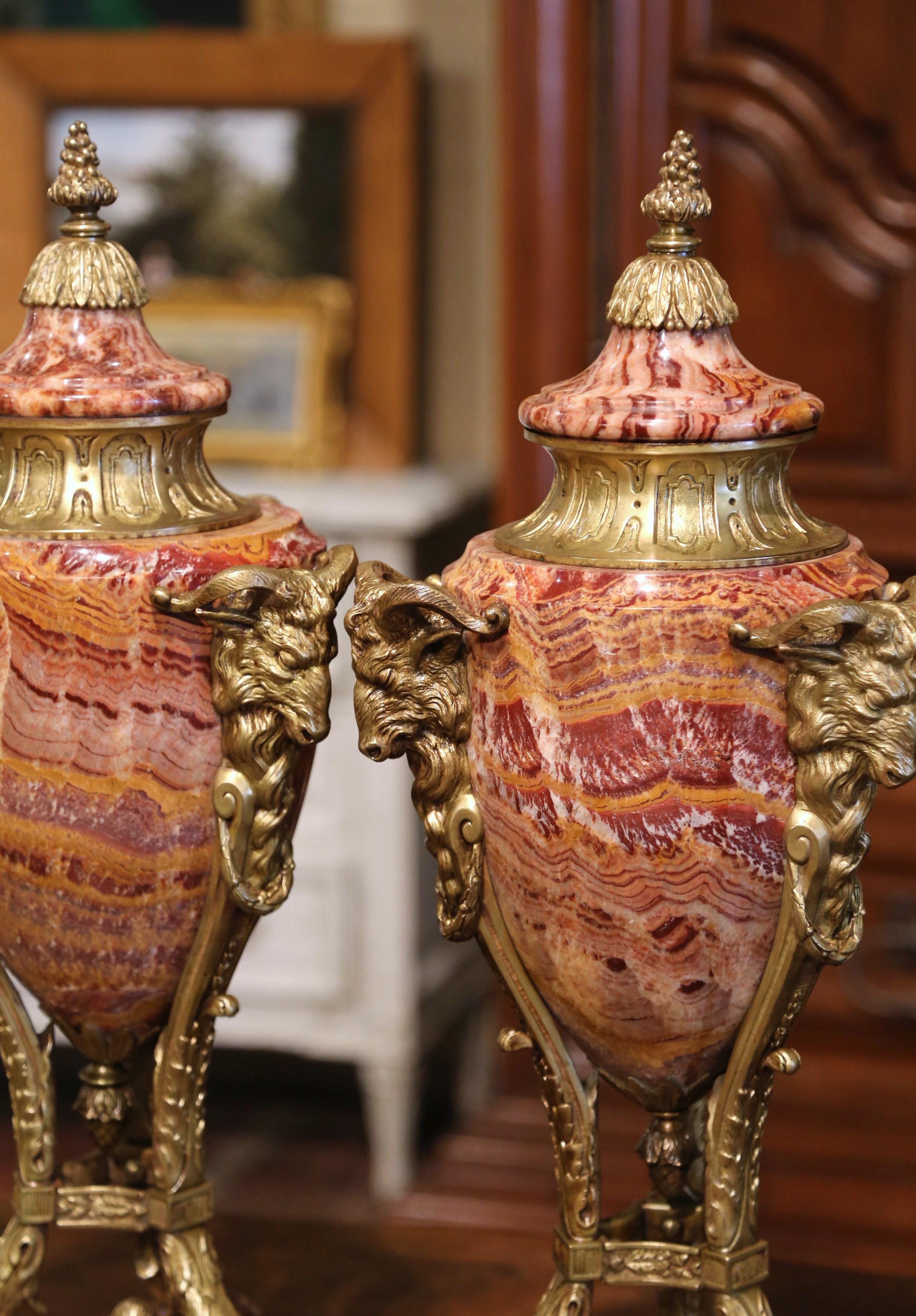 Decorate a mantel or buffet with this important pair of antique covered urns. Crafted in Belgium circa 1870, each tall vessel stands on triangular shape marble bases ending with delicate round bronze feet. Each Belgian vase is dressed with a dome