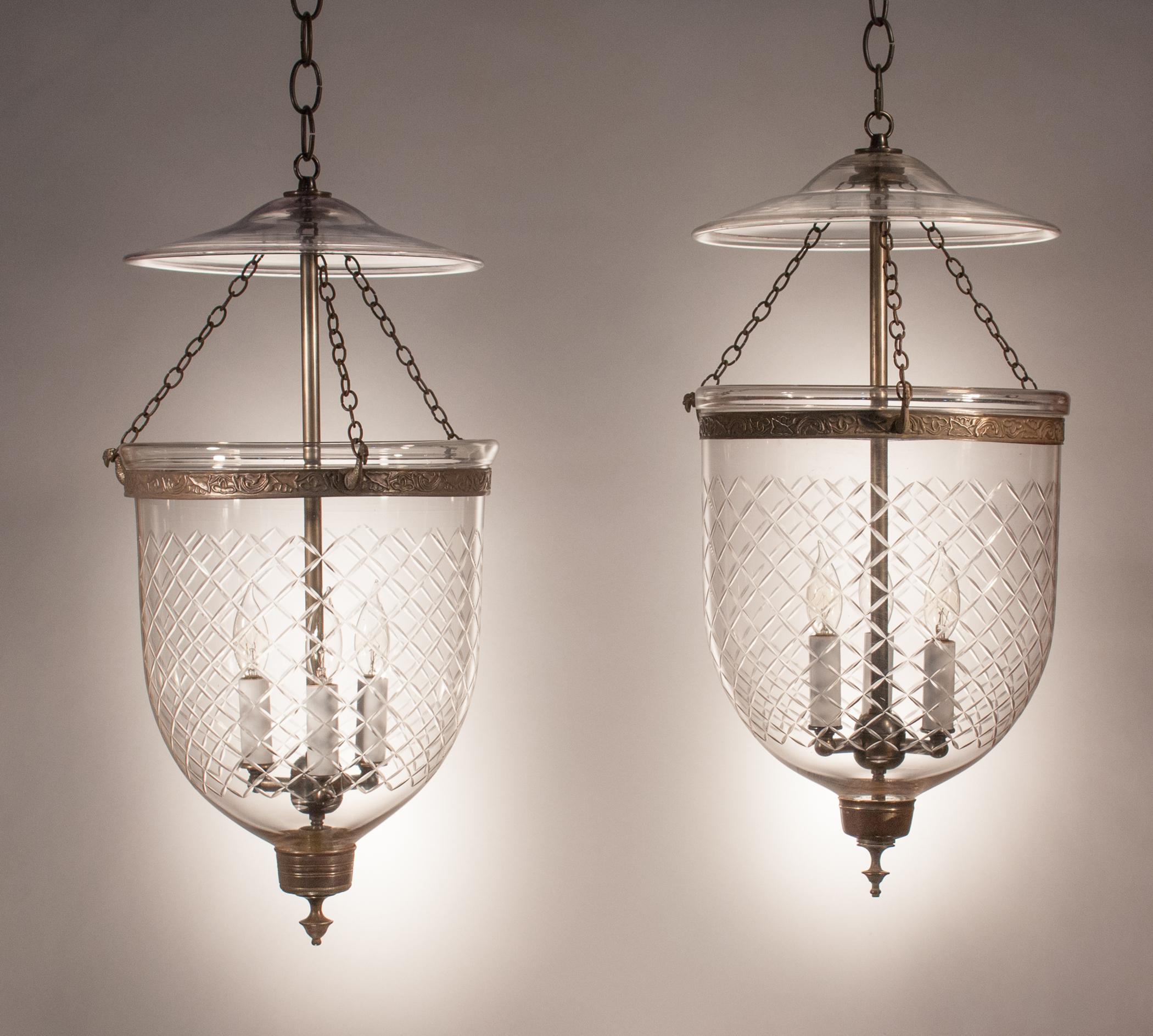 An authentic pair of antique bell jar lanterns featuring excellent quality hand blown glass. These circa 1870, medium-sized pendants are etched with a Waterford-style diamond motif and feature their original smoke bells and brass finials. Note that