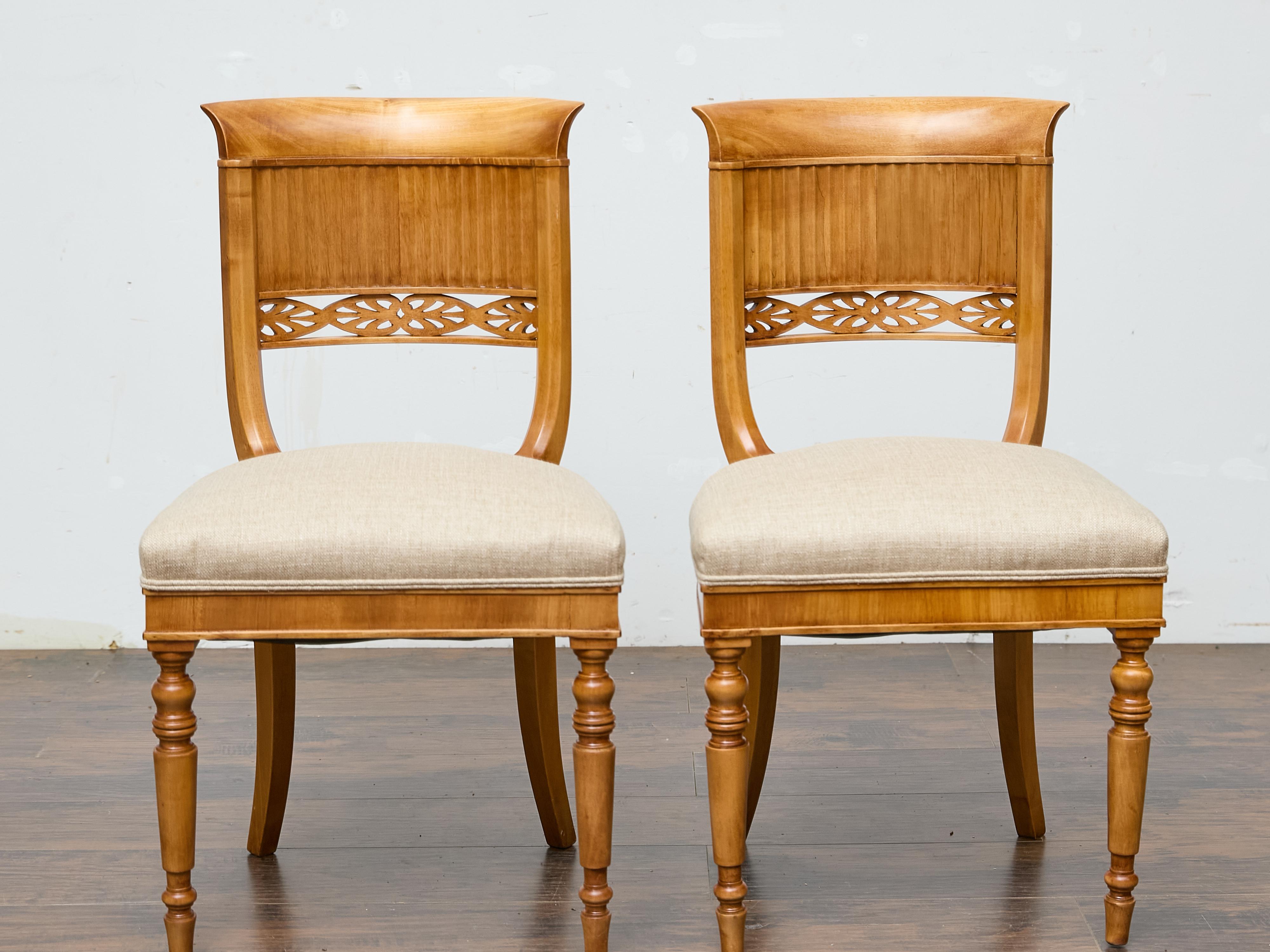 Una coppia di sedie Biedermeier austriache del XIX secolo, magistralmente realizzate in noce pregiato, che uniscono eleganza e ornamenti sobri. Il binario superiore curvo, delicatamente svasato verso l'esterno, incornicia un raffinato schienale