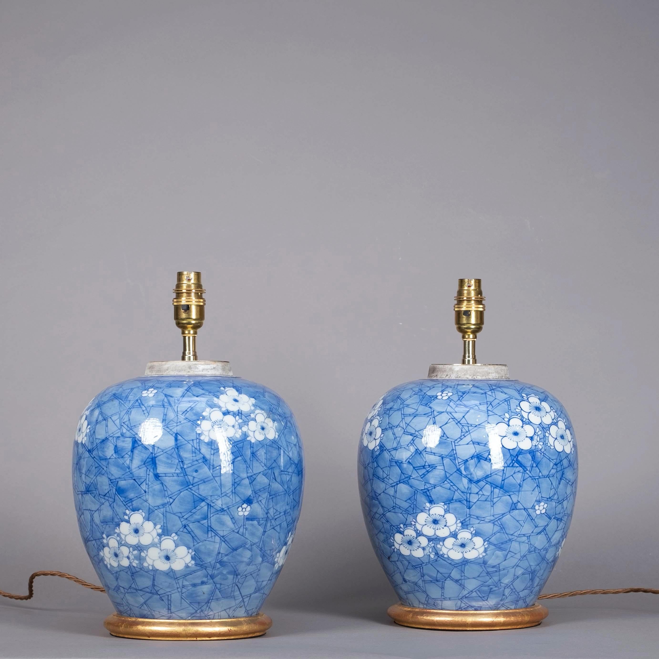 A pair of late 19th century blue and white porcelain ginger jars, the bulbous bodies decorated with cherry blossoms upon a “cracked ice” ground.

Now mounted as lamps and set upon turned giltwood bases.

Dimensions listed refer to height up to