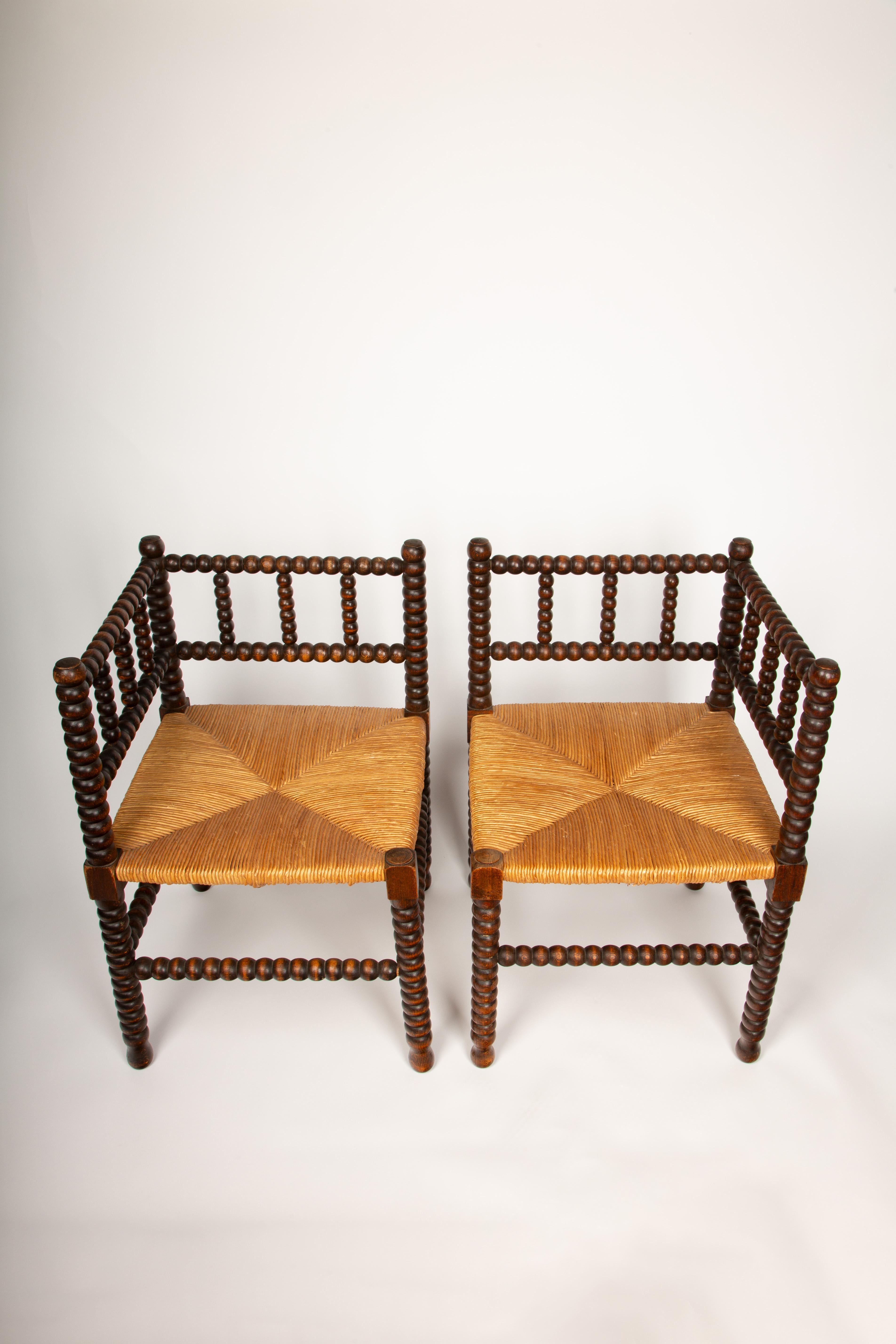 Enhance your living space with this exquisite pair of 19th-century corner chairs, showcasing a unique bobbin-turned wood design. These chairs are a fine example of traditional craftsmanship, featuring intricately turned wooden spindles that create a