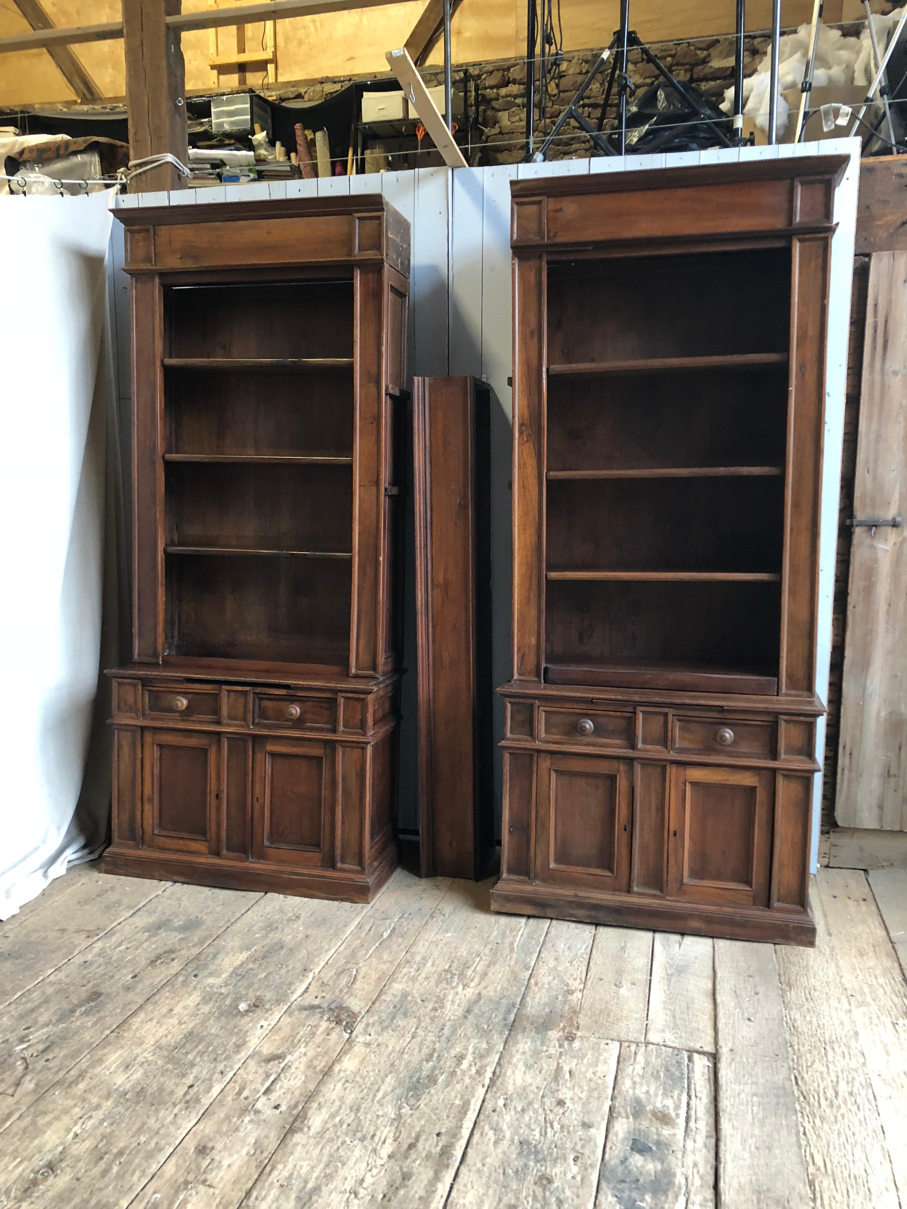 A pair of Napoleon III walnut bookcases with an upper cornice and 2 long shelves between them, mid-19th century, French. The tall upper bookcases have 3 shelves each and are above lower 2-door cabinets with 2 drawers above. Great store display or as