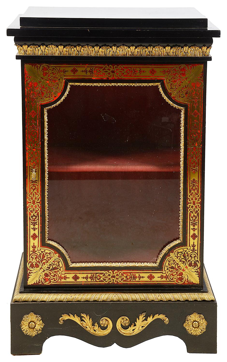 A good quality pair of French 19th century Boulle side cabinets, having ebonized tops and sides, gilded ormolu mounts, glazed doors to each with red velvet interior and shelf. Classical motif brass inlaid decoration to the red stains tortoiseshell,