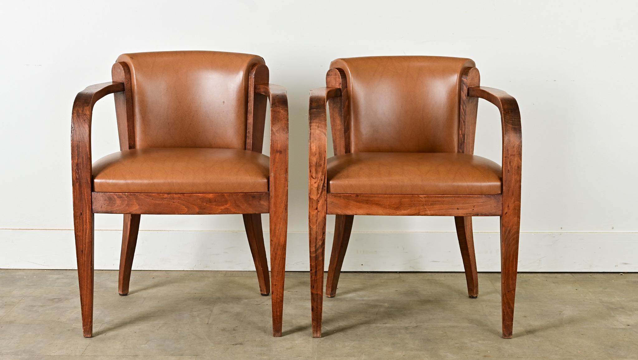 Cette belle paire de bridges français présente le raffinement caractéristique de la fin du XIXe siècle, avec ses bras en chêne et sa coupe élégante. Le revêtement actuel est un cuir synthétique couleur caramel, agrémenté de têtes de clous en laiton