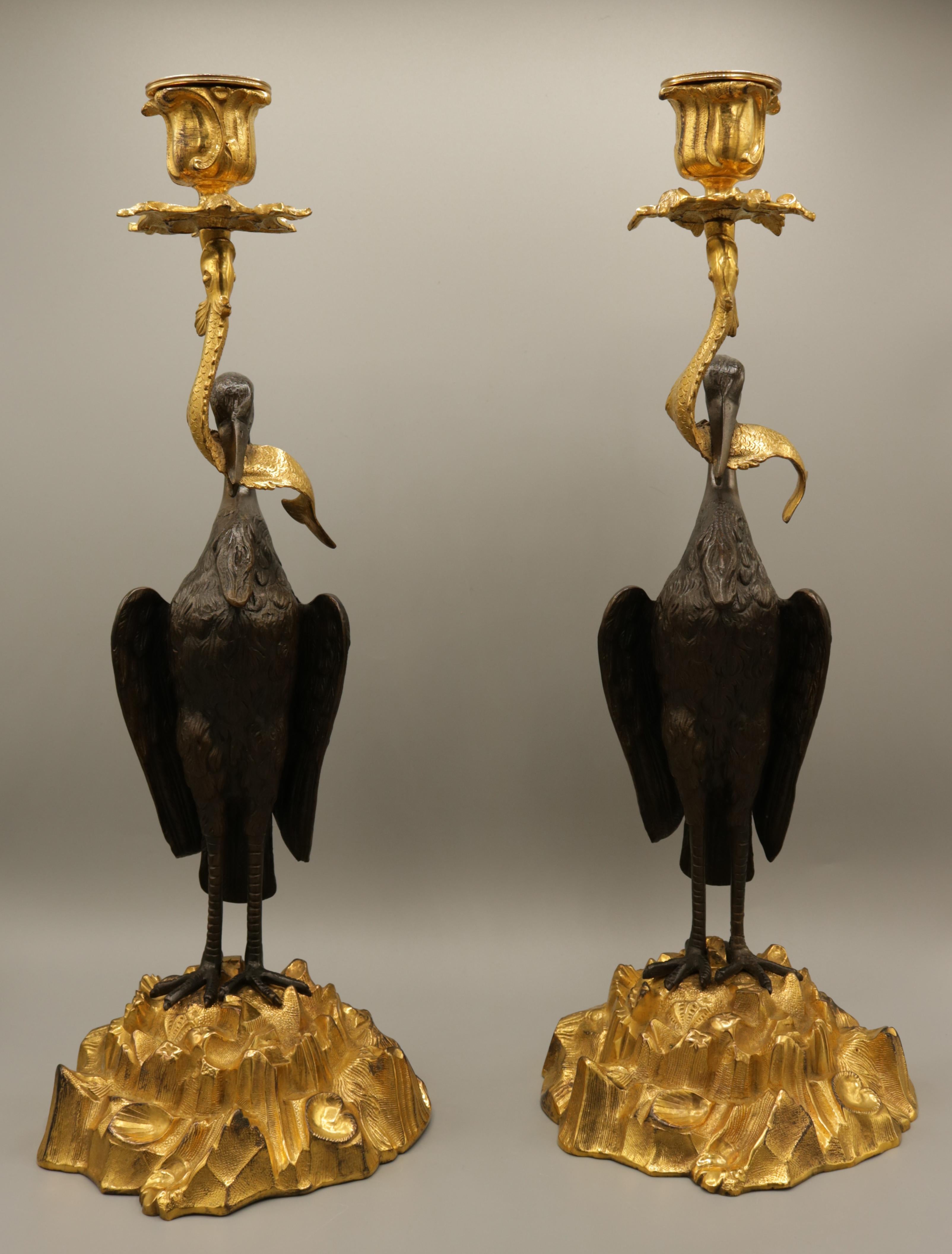 An unusual pair of mid-19th century bronze and ormolu candlesticks, having rococo candleholders above well cast herons holding stylised fish, raised on rock and shell bases, retaining original iron weights.
(Probably by Thomas Abbott of Birmingham.)