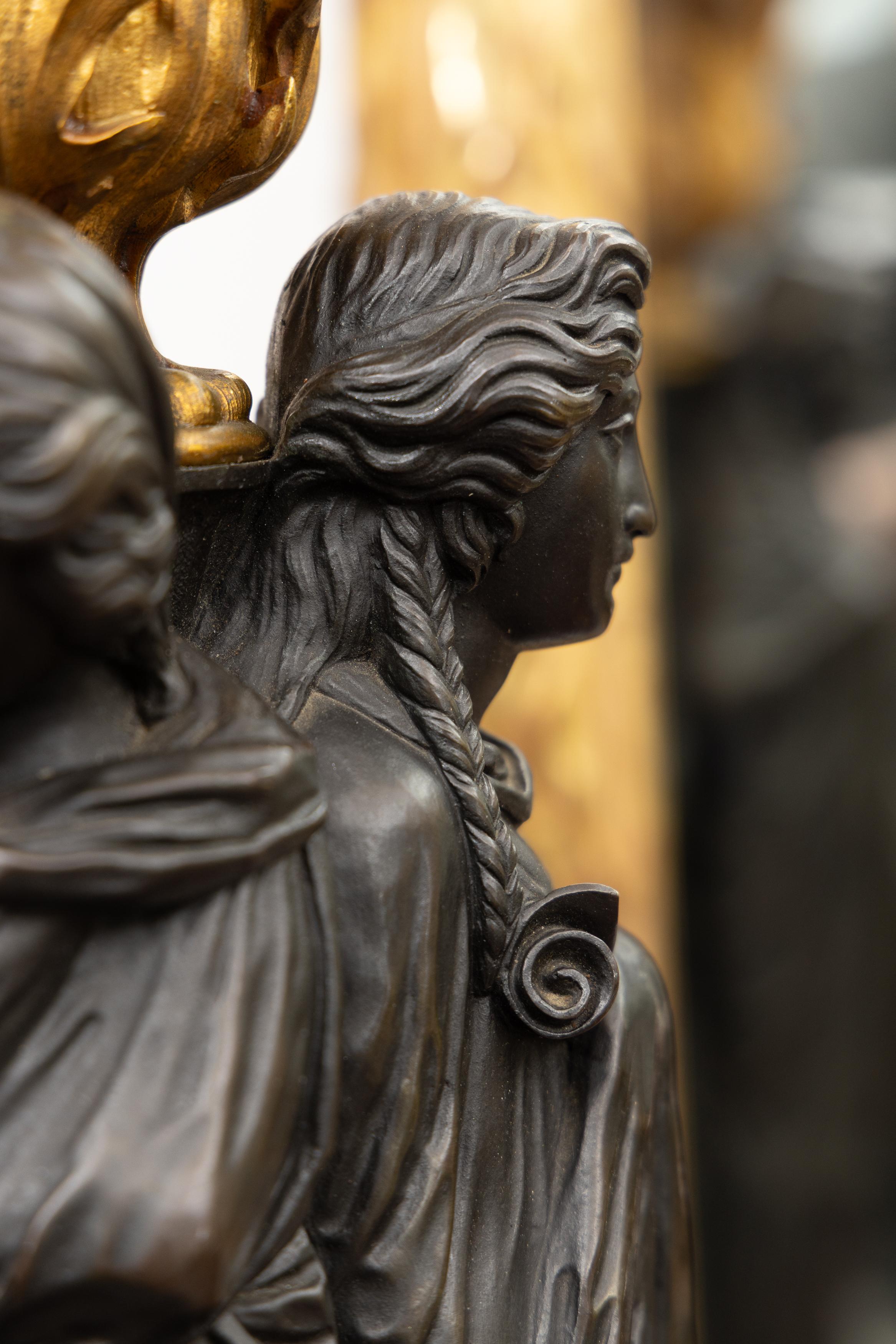 This is a stately pair of 19th century bronze figural sculptures of the Three Graces, daughters of Zeus, as lamps. Each lamp depicts a group of three women in classical drape situated on a black hexagonal marble and parcel gilt base. In Greek