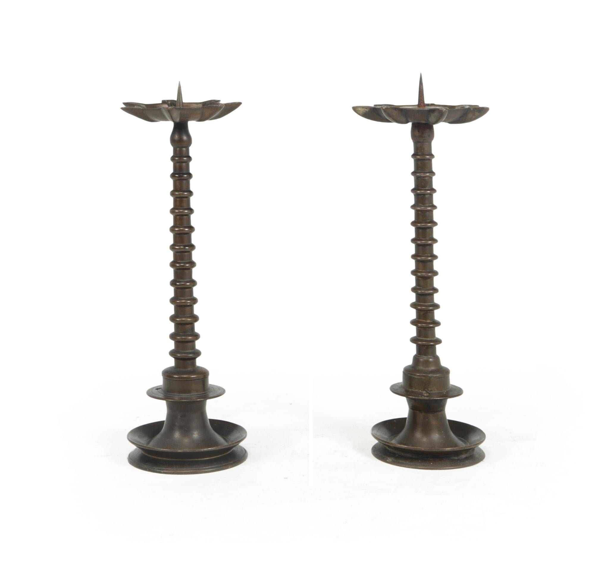 A near pair of solid bronze, large and heavy, bobbin stem, candlesticks. In very good condition with age related marks and wear, overall very good condition, two holes have been drilled into each candlestick as they may have been converted into