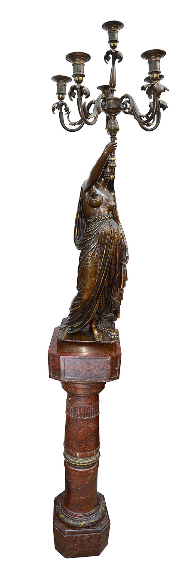 Coppia di figure orientali in bronzo dorato e patinato che reggono candelabri. Ogni figura orientale maschile o femminile semi-vestita, la donna in piedi accanto a una scatola di gioielli, l'uomo con in mano un ventaglio. Poggia su una base