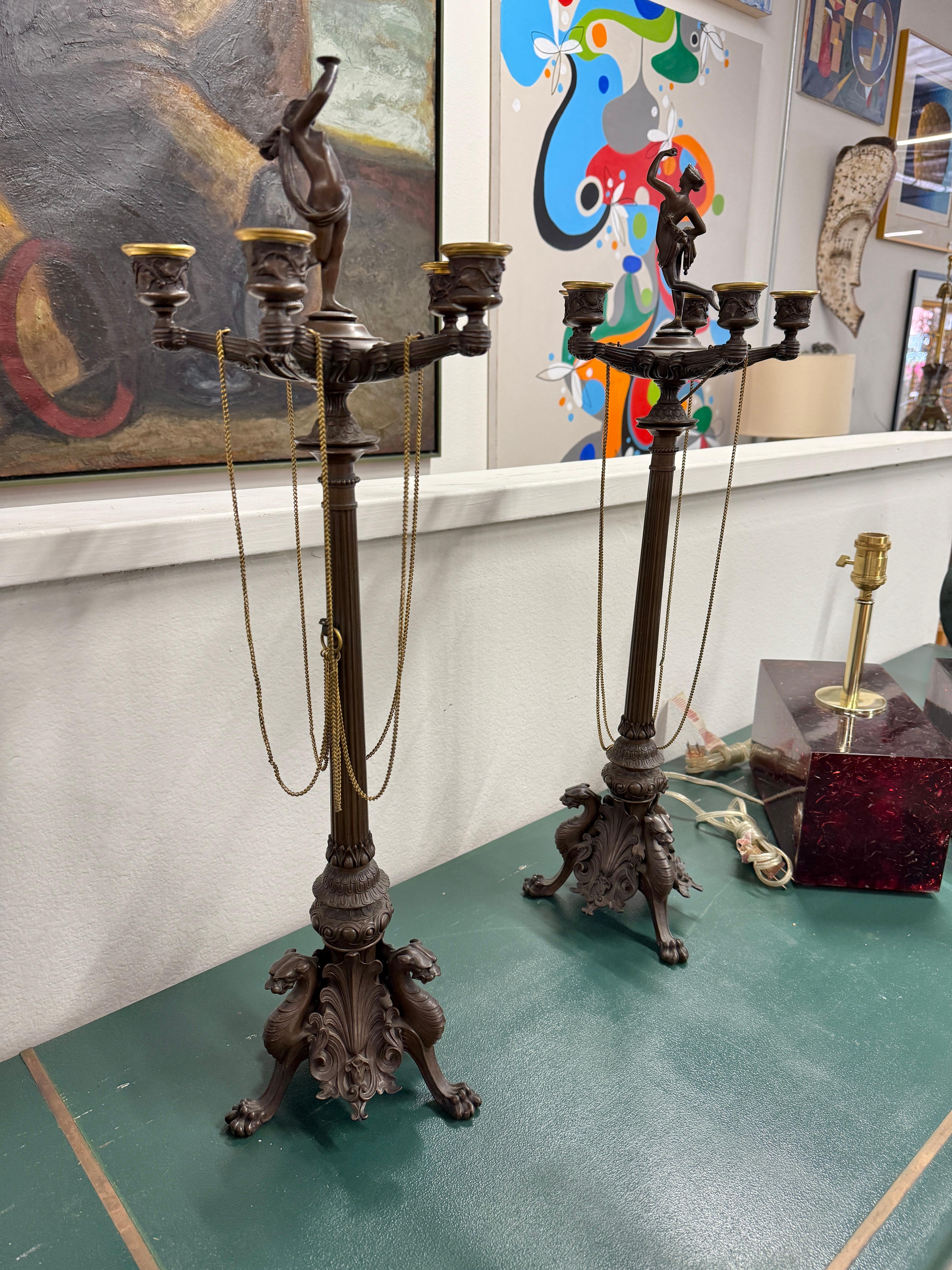 Una squisita coppia di candelabri in bronzo francesi neoclassici del XIX secolo. Ciascuno di essi presenta 5 portacandele e una figura femminile centrale in cima. Tutti i bobeches sono presenti. Le catene possono essere sostituite, poiché sono in