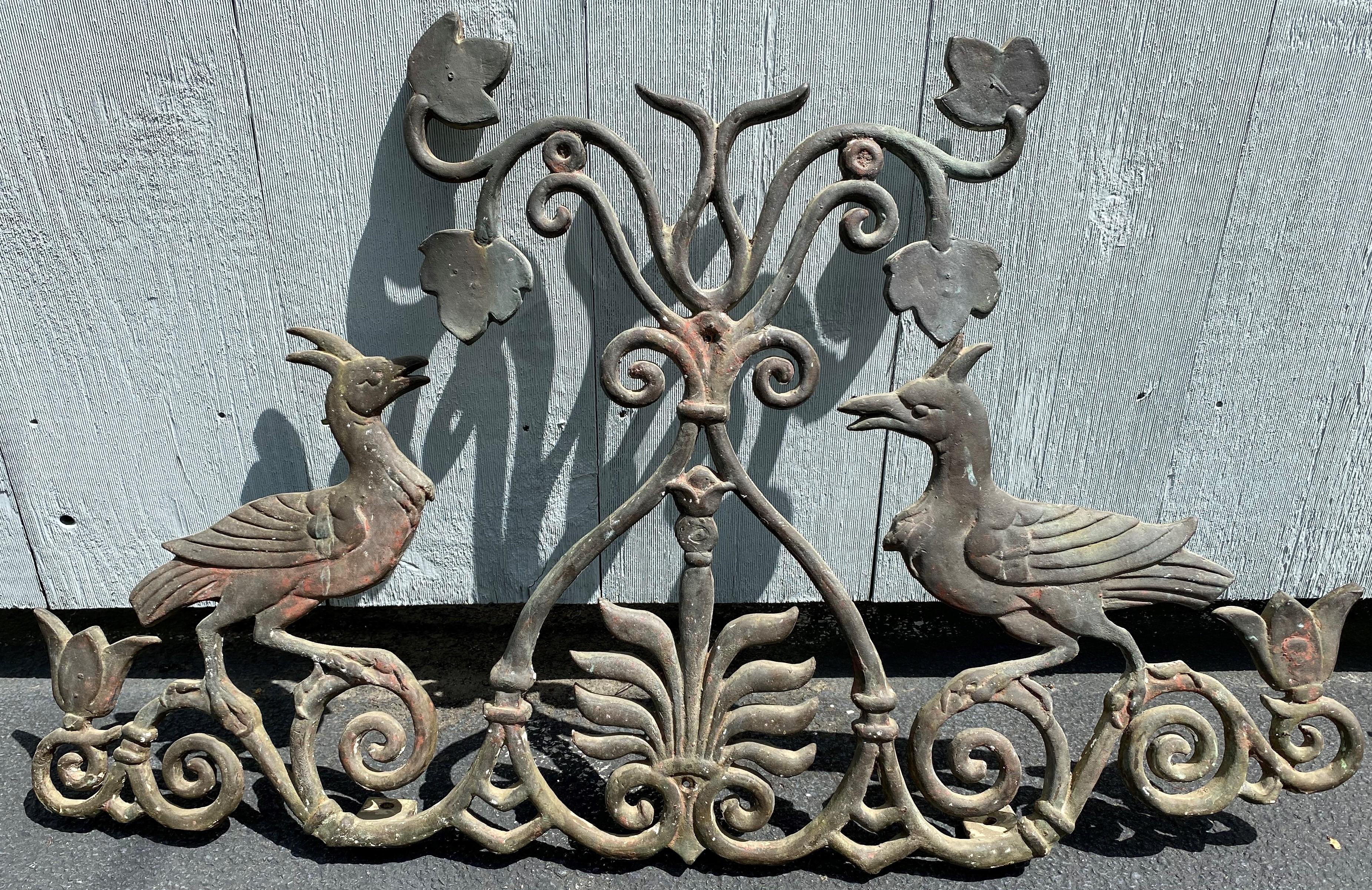 A wonderful matching pair of scrollwork bronze window guards featuring birds and flowers, dating to the 19th century, with great verdigris and patina, light rust and some additional white paint on one. They have two mounting tabs on the base for