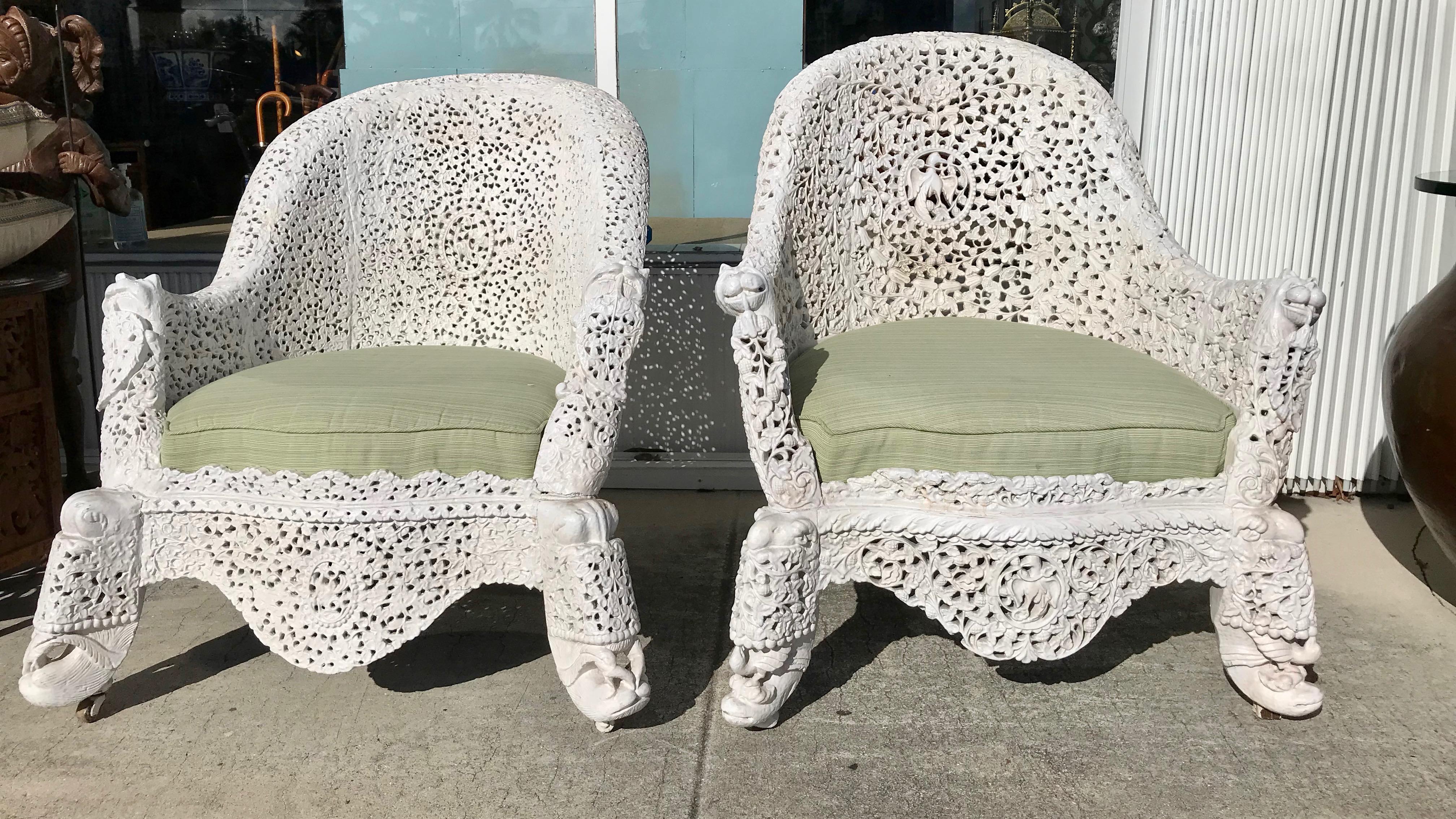 Elaborately and ornately carved and generously scaled hardwood chairs-
- his and hers as one is somewhat larger.
The chairs are appointed with tiger heads and raised upon elephant motif
feets. They are coated with white paint , as is the fashion,