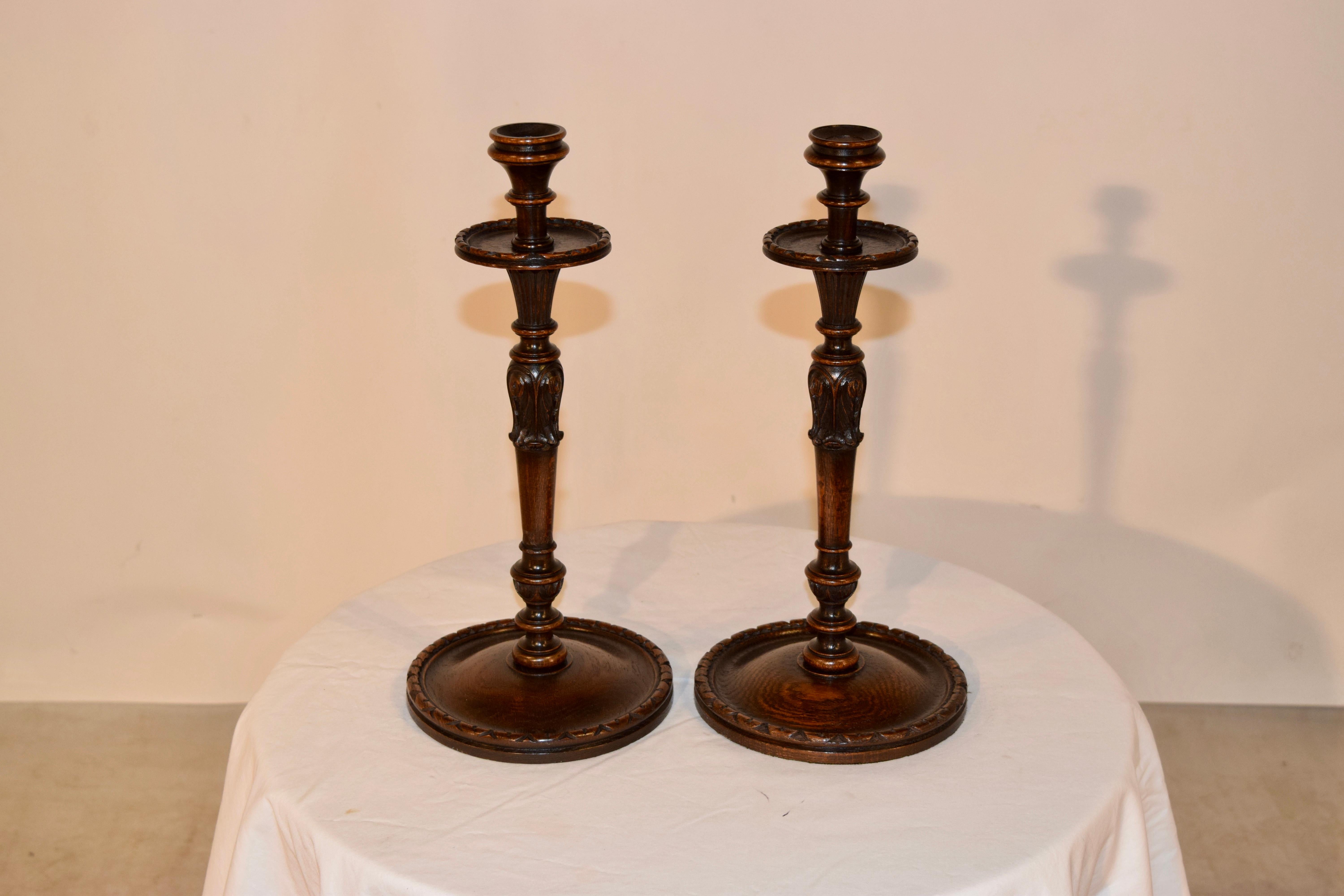19th century pair of unusually large English oak candlesticks. They have wonderfully turned tops and bobeches, which have carved decorated edges, following down to a bulbous turned and carved stem over a large turned base with carved edge.