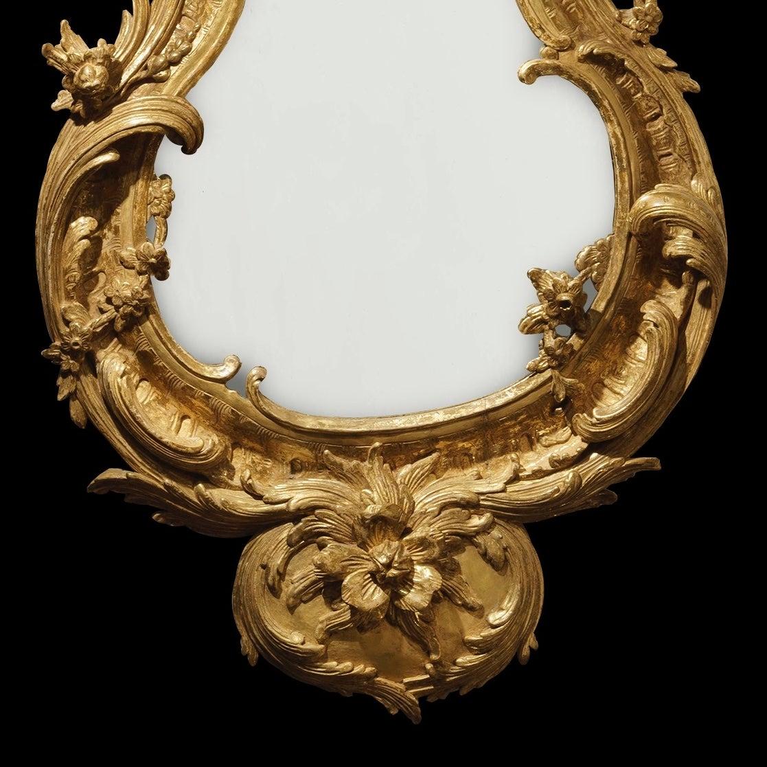 A pair of George II style mirrors

Constructed in carved giltwood, the wasted teardrop shaped mercury plates housed within asymmetrical conforming frames in the George II manner richly carved with scrolling foliates and flowering branch work;