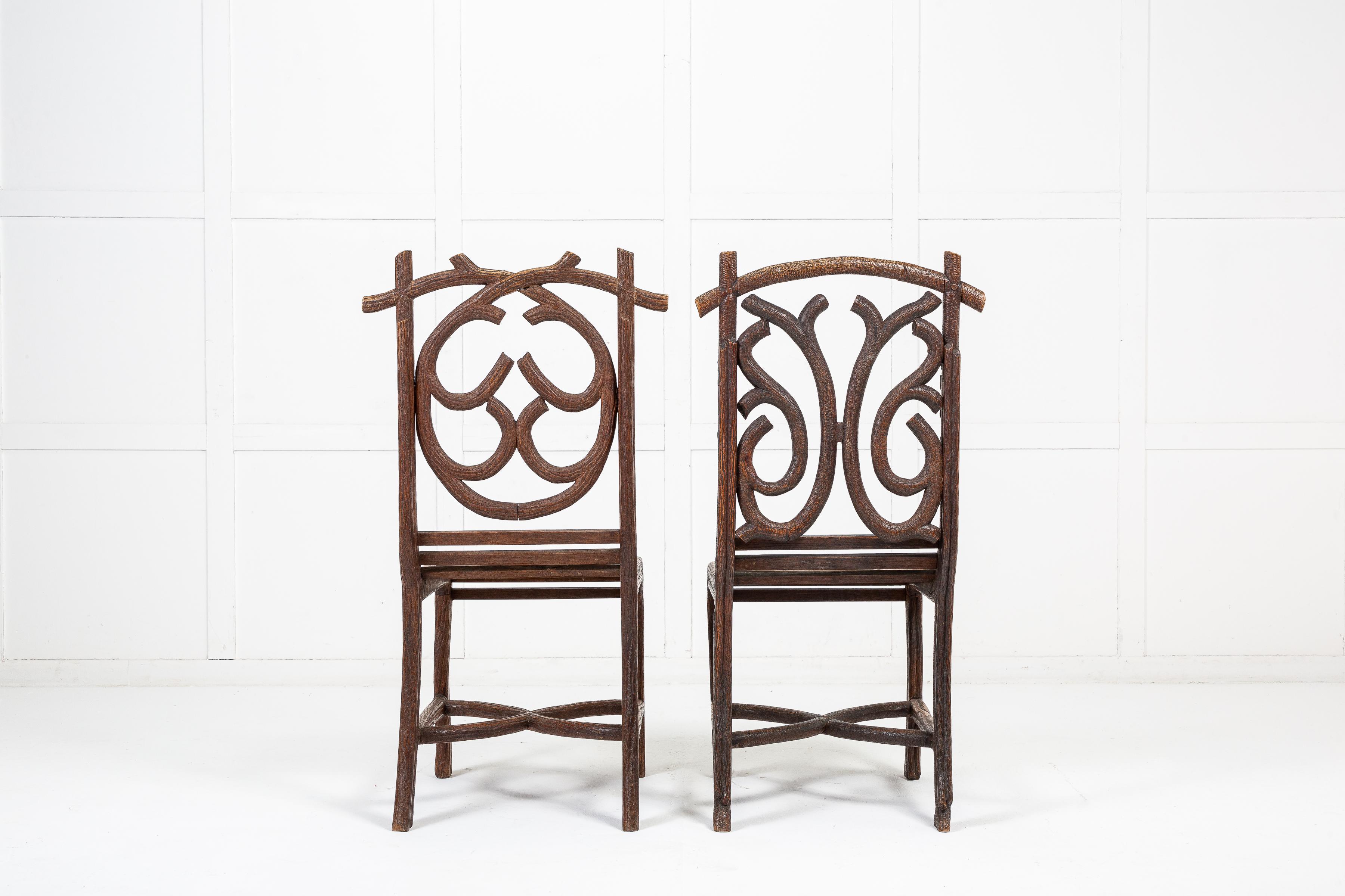 An unusual pair of 19th century carved linden wood chairs. The backs and legs are carved in the form of tree branches and vines adorned with acorns and leaves. Having slatted bench seats joining the frame and traditional curved, cross stretchers