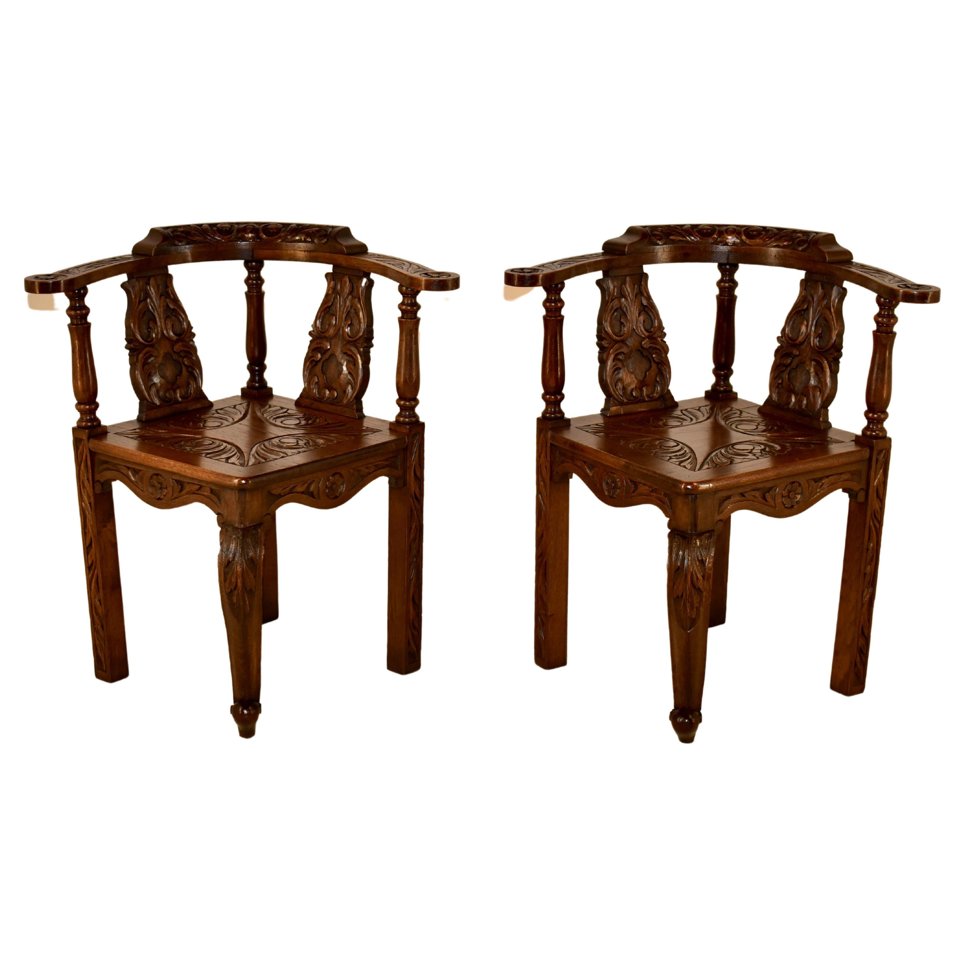 Pair of 19th century carved oak corner chairs from England with a wonderfully carved back, supports and arms, all depicting acanthus leaves and scrolls. The seats have wonderful carving as well over a single cabriole leg in the front and three stout
