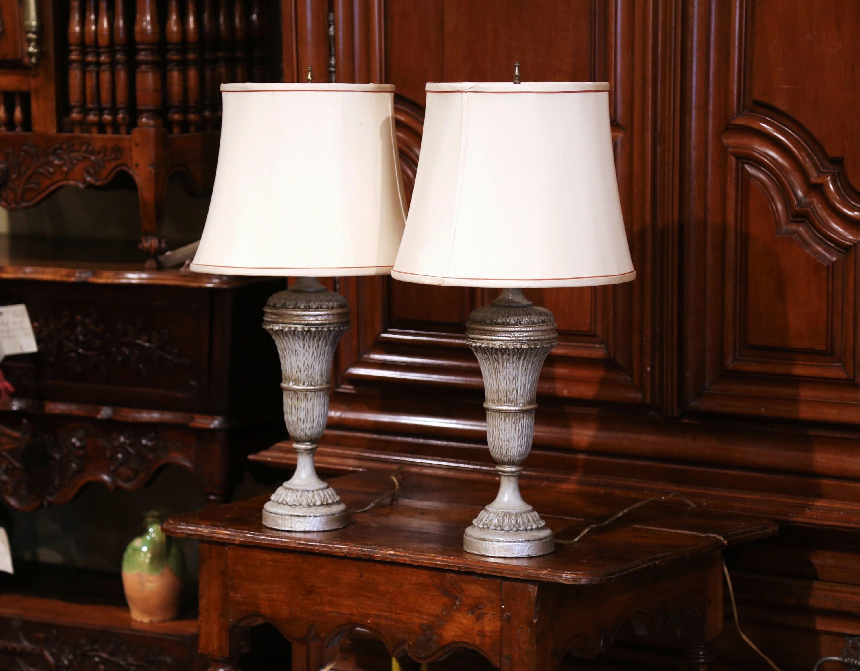 Crafted in France, circa 1890, these antique lamps would make a nice addition to your bedsides tables or entry buffet. Each lamp has a carved urn-shaped base, brass fitting, and a hand-painted finish in a green and silver palette. Both light