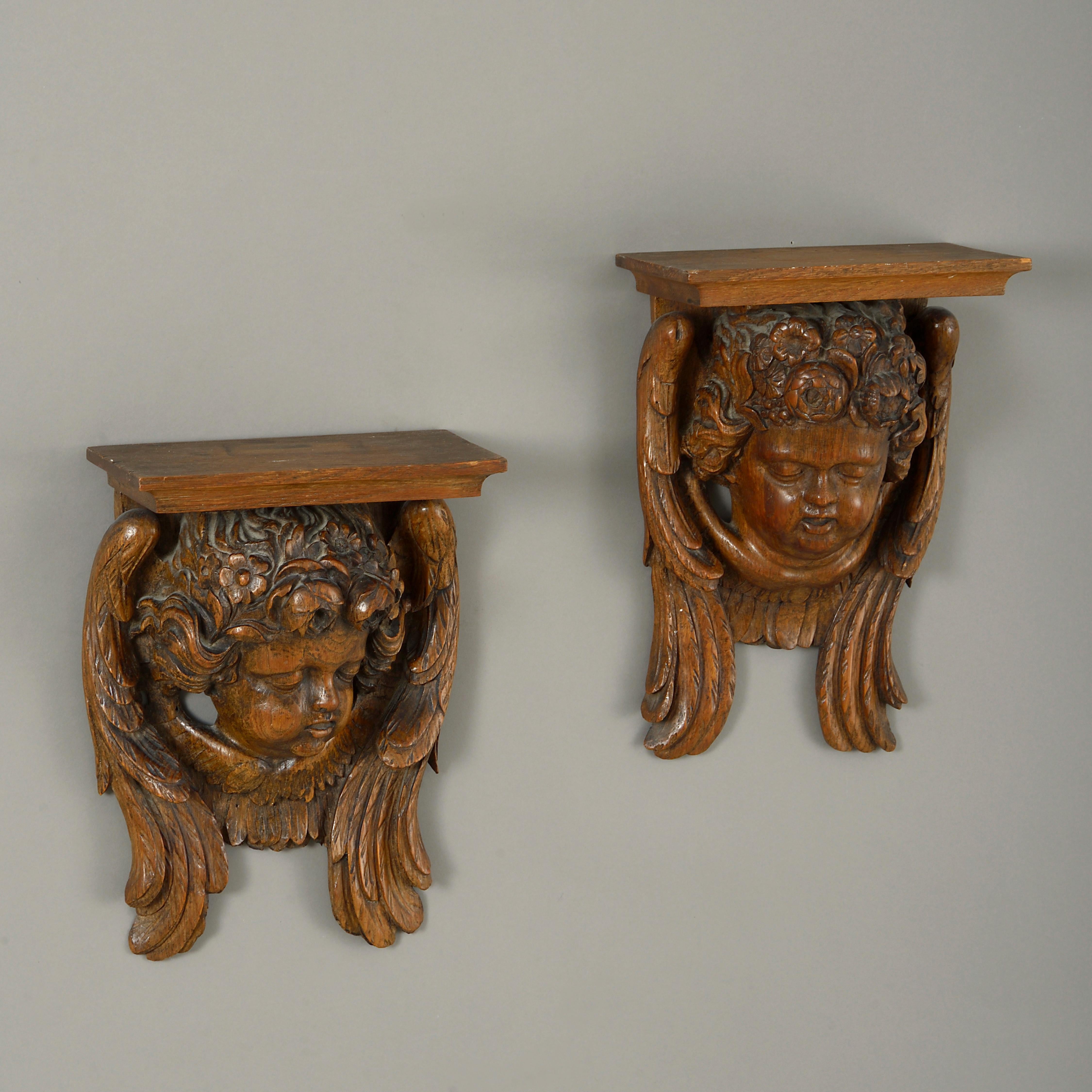 A pair of 19th century carved oak wall brackets, having lintel shelves above putti and with floral head dress and wings in the Baroque manner.