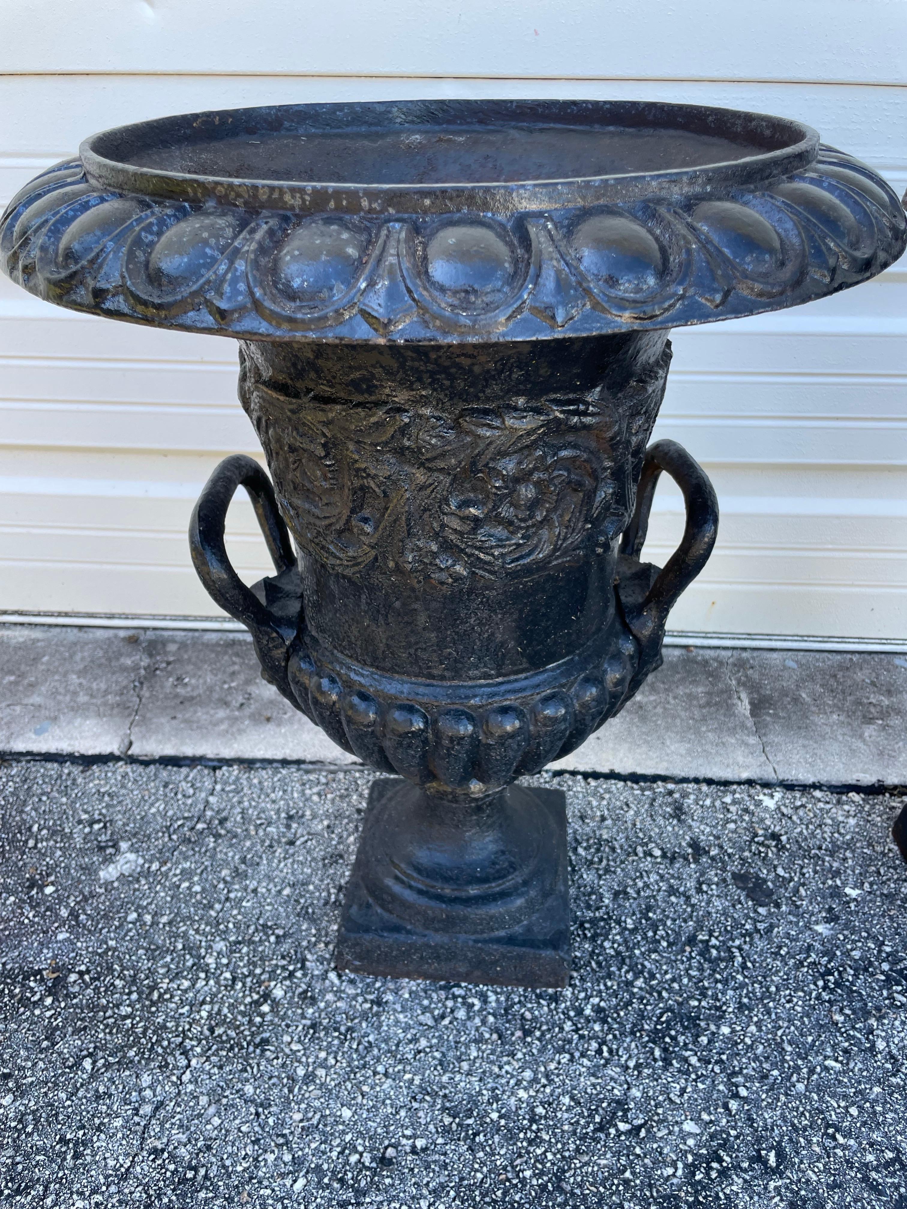 Coppia di antiche fioriere neoclassiche in ghisa con disegni di ghirlande e manici.