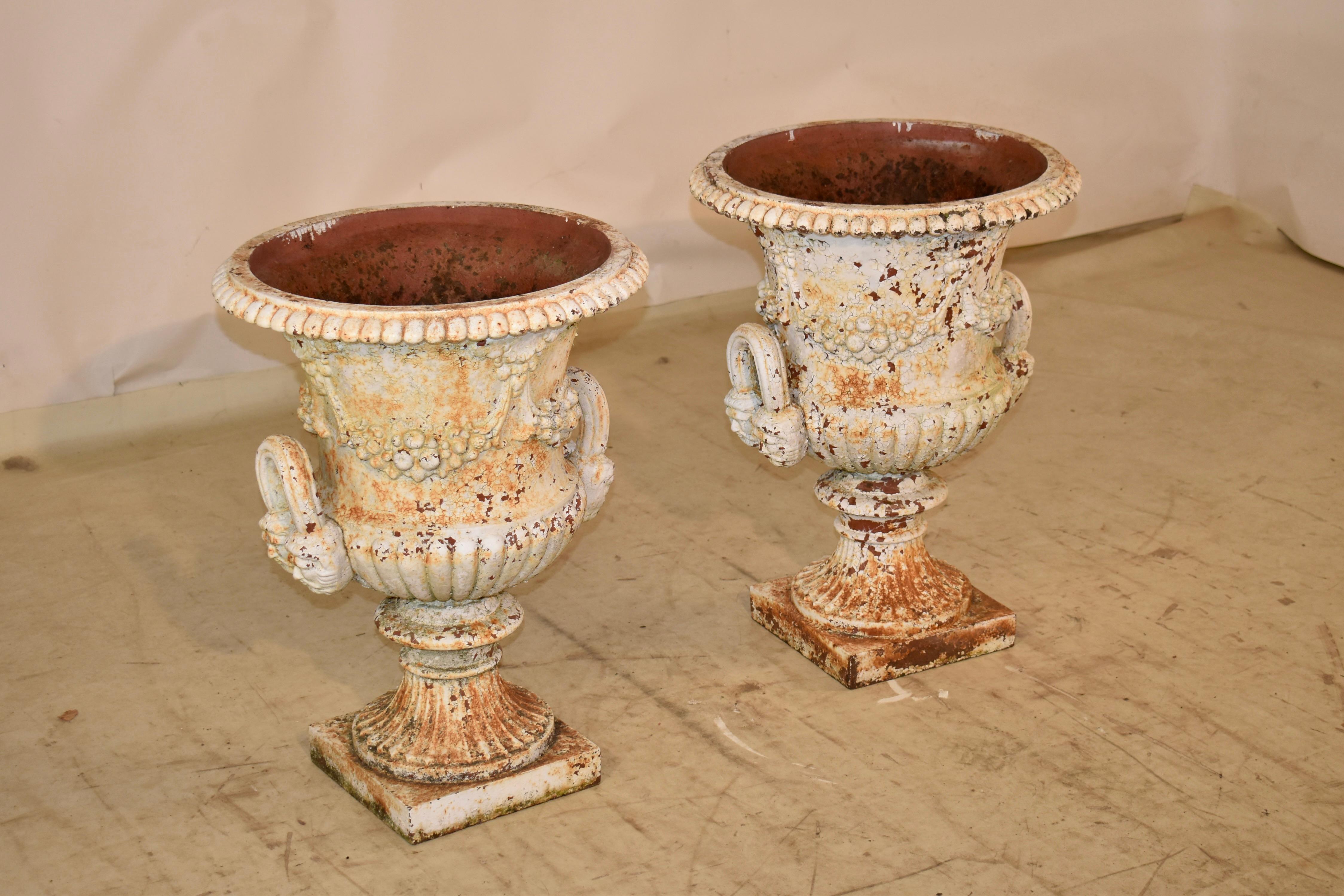 Coppia di fioriere in ghisa del XIX secolo provenienti dall'Inghilterra.  I vasi sono molto decorati con festoni floreali e bordure, che ne accentuano la bella forma.  Le maniglie hanno la forma di due facce con un arco di raccordo a reticolo.  Sono