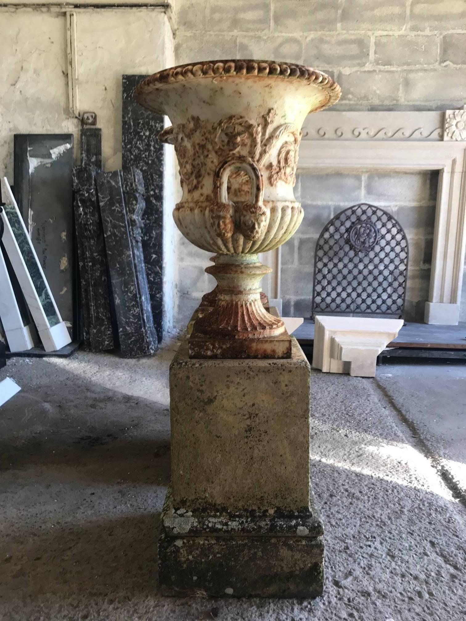 A pair of large 19th century, early Victorian, cast iron urns on terracotta stands. They were taken from a grand house in Hamptead, London.
The cast iron urns with scrolling floral freeze with masked handles above is scalloped terracotta base on